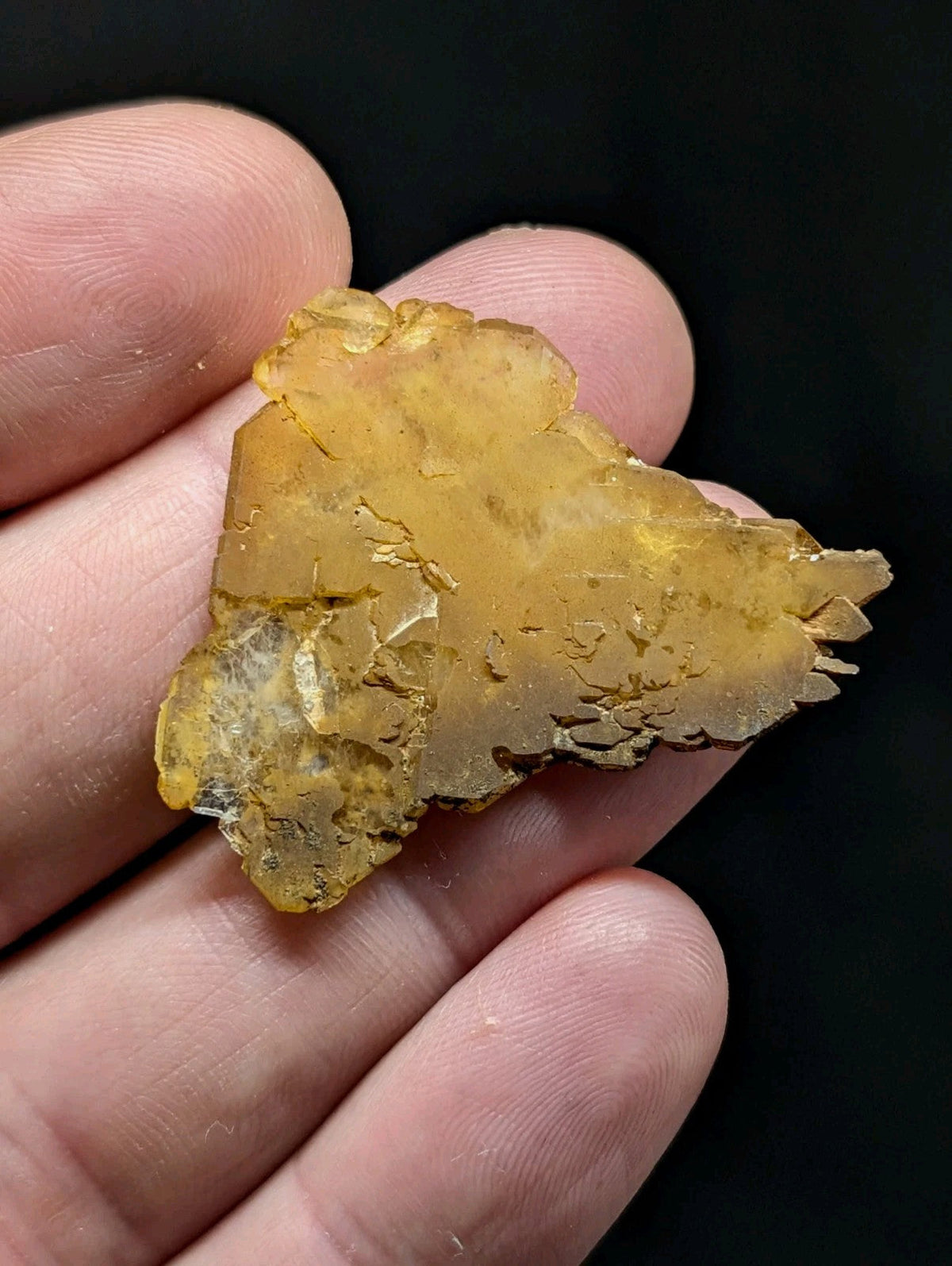 A translucent amber-colored, irregularly shaped mineral specimen with a rough, crystalline surface.