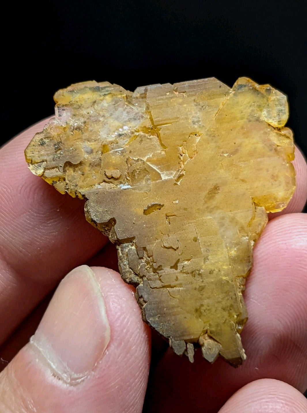 A translucent golden-yellow mineral specimen with a crystalline, faceted surface and natural fractures.