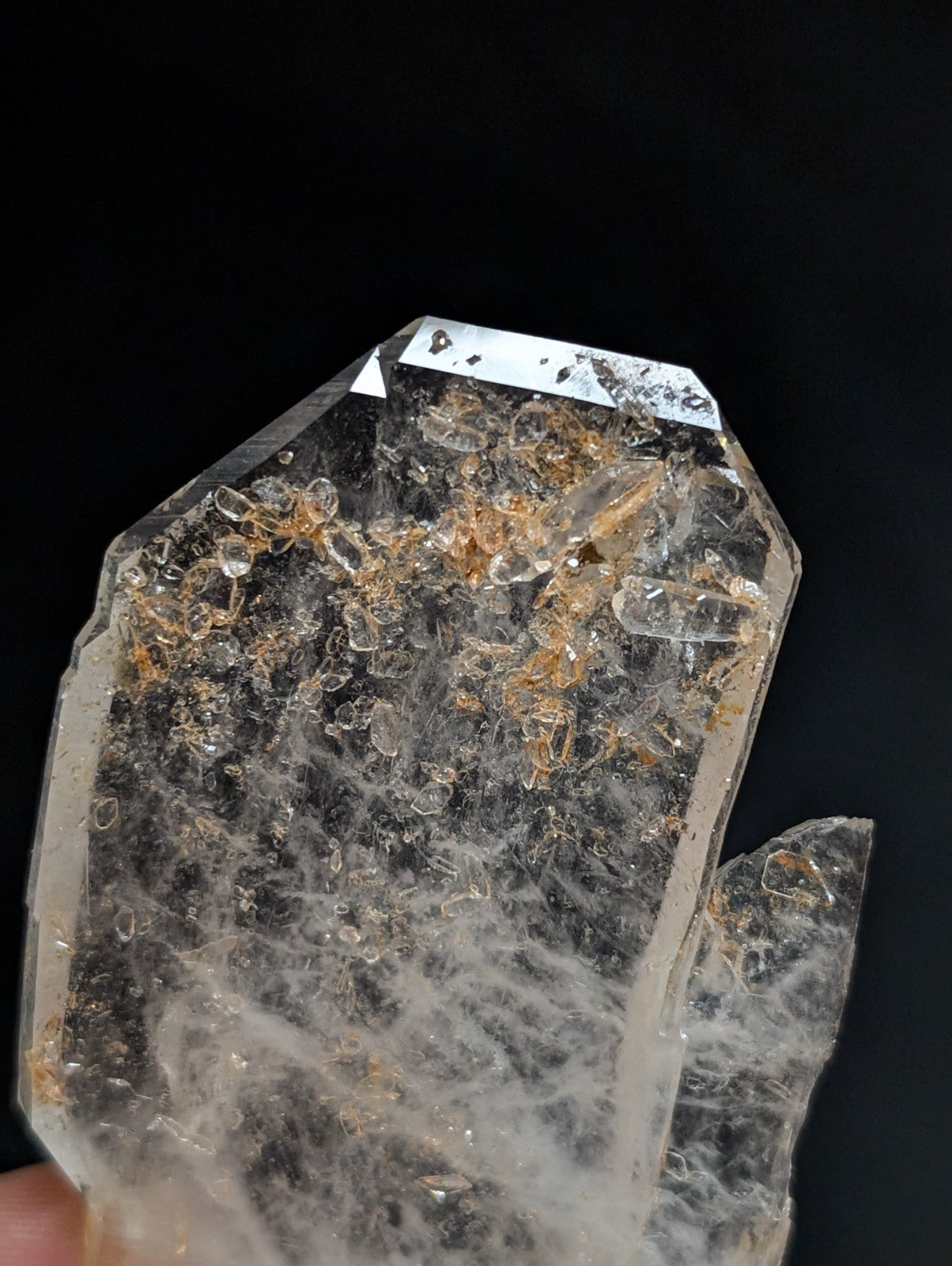 A translucent, clear quartz crystal with golden inclusions and a faceted top.