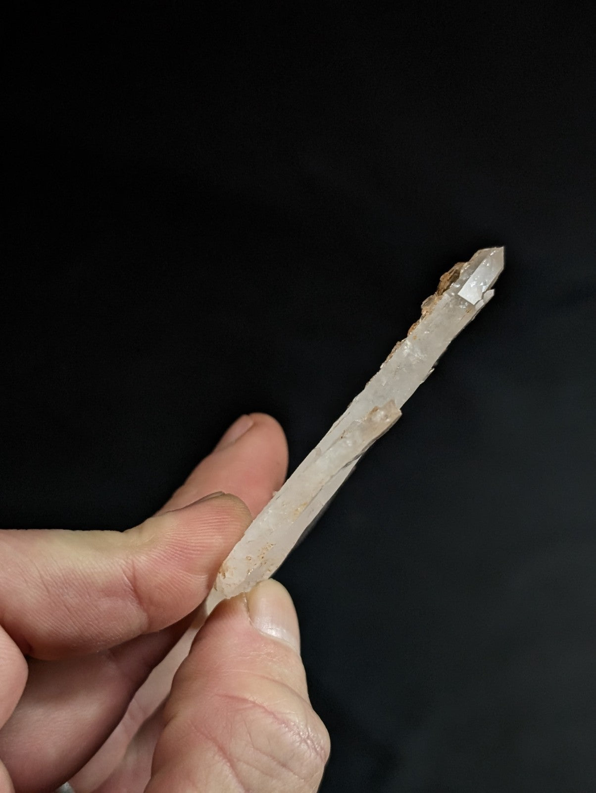 A translucent, pale quartz crystal with a pointed tip and natural striations.