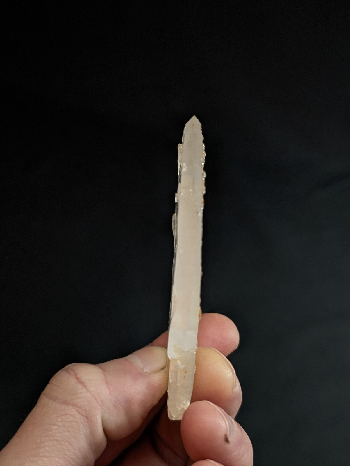 A translucent, pale quartz crystal with a pointed tip and natural facets.