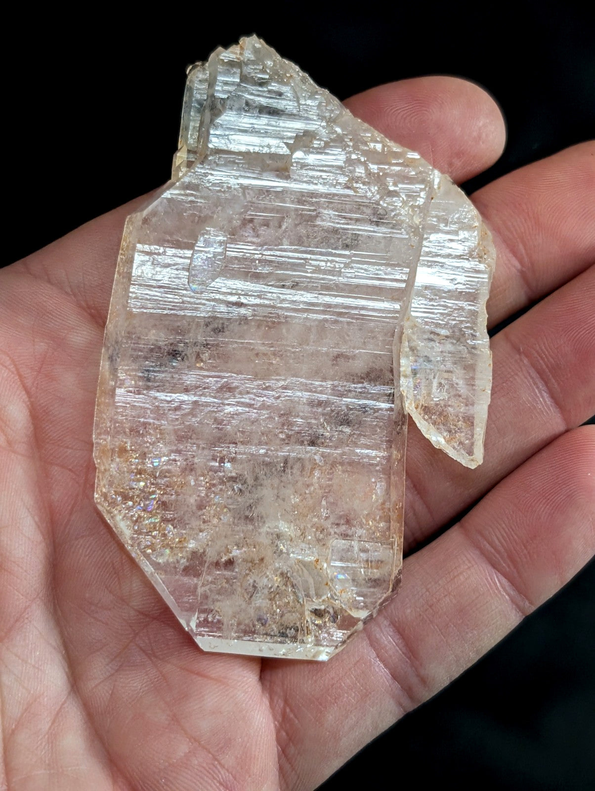 A translucent, pale yellowish crystal with distinct horizontal striations and a rough, jagged edge.