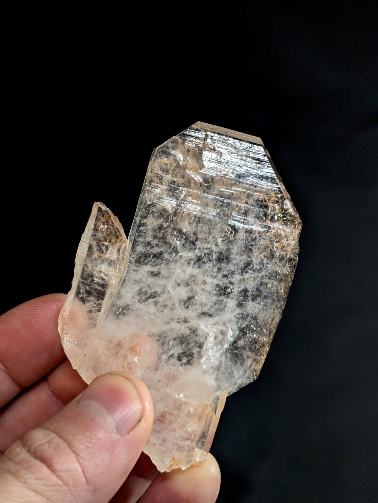 A translucent, pale quartz crystal with a rough, jagged surface and subtle internal striations.