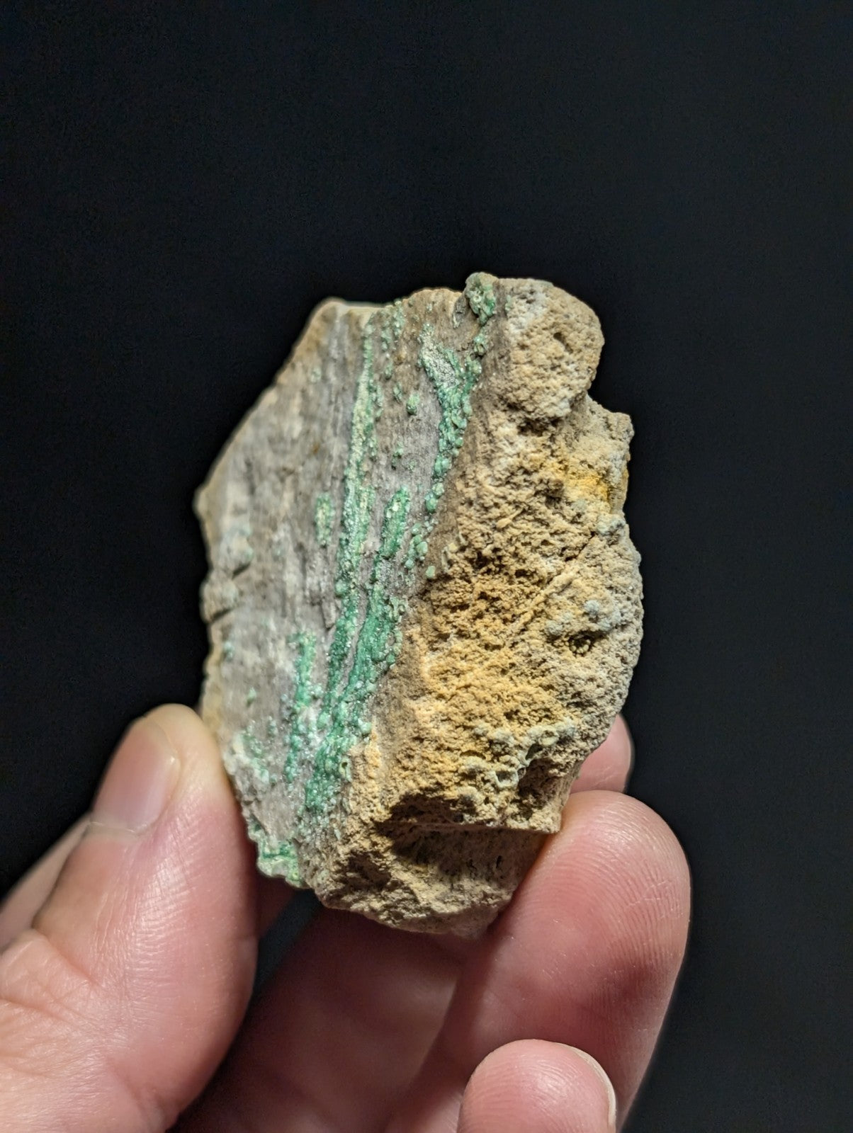 A weathered, irregularly shaped fragment of ancient metal with a patchy green patina and yellowish rust streaks.