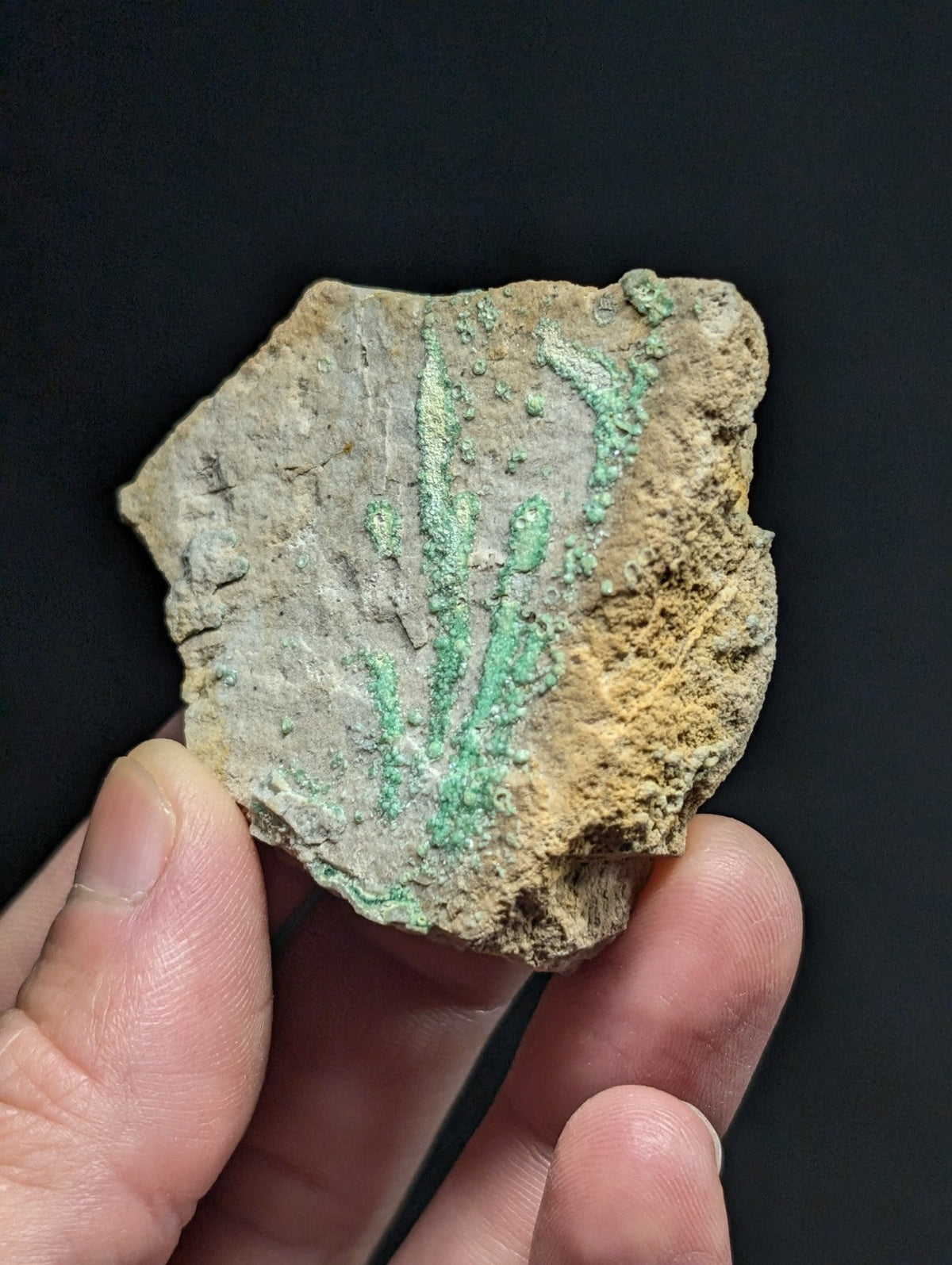 A weathered, irregularly shaped fragment of ancient metal with a textured surface and patches of green patina.