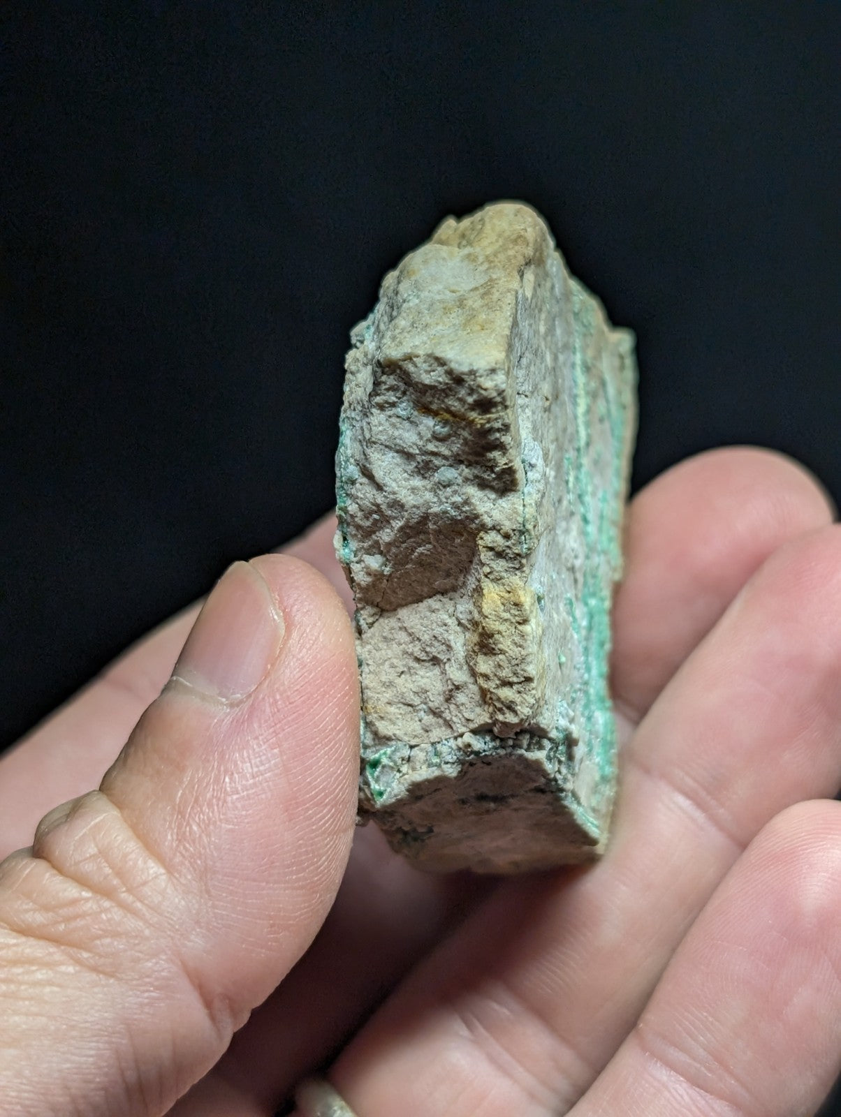A weathered, irregularly shaped piece of ancient bronze with a green patina and patches of yellowish corrosion.