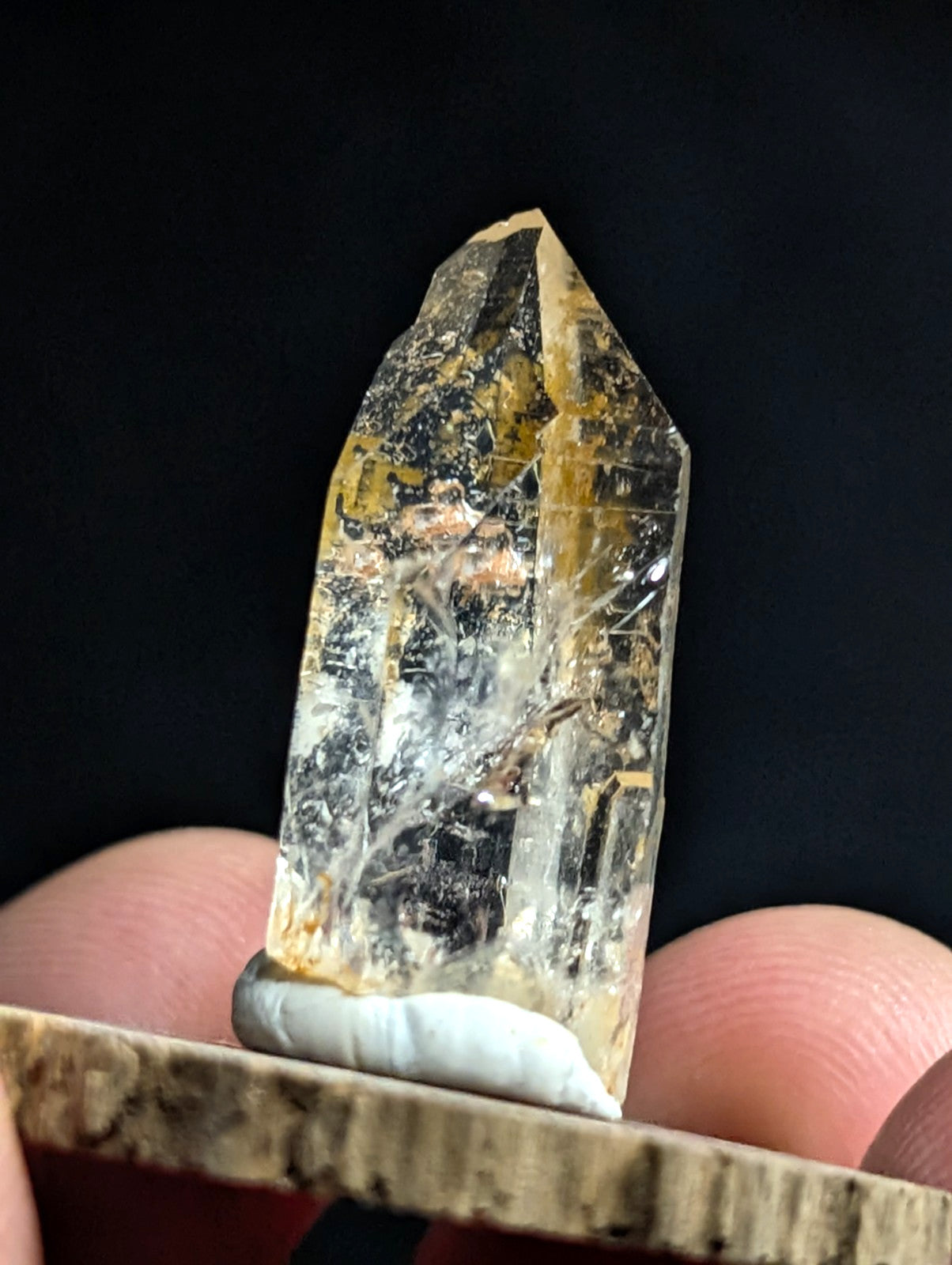 A translucent golden-yellow crystal with natural inclusions and a pointed, faceted top.
