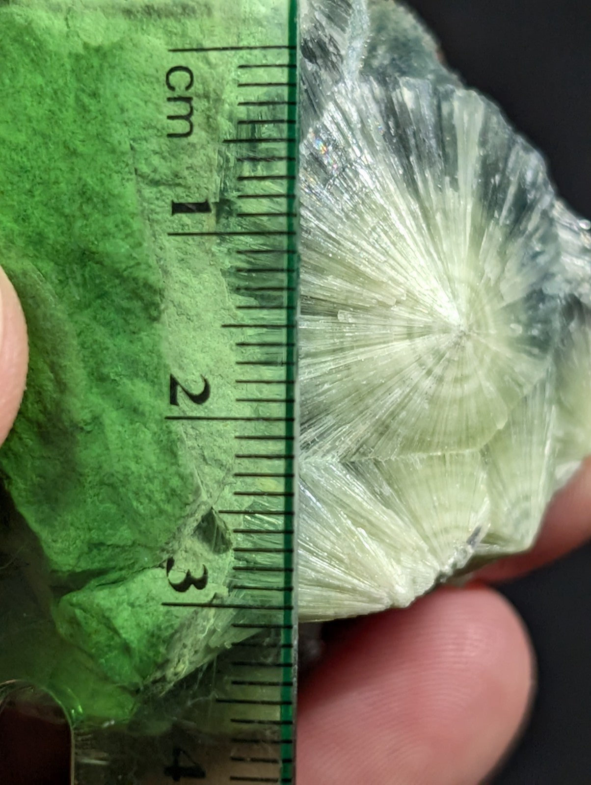 A translucent, pale green mineral specimen with radiating crystalline structures.