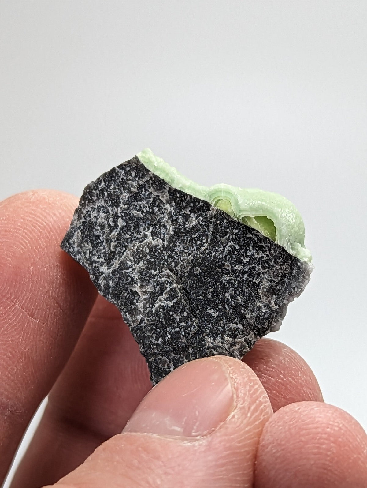 A dark, speckled chocolate bar with a mint-green filling peeking out from its broken edge.