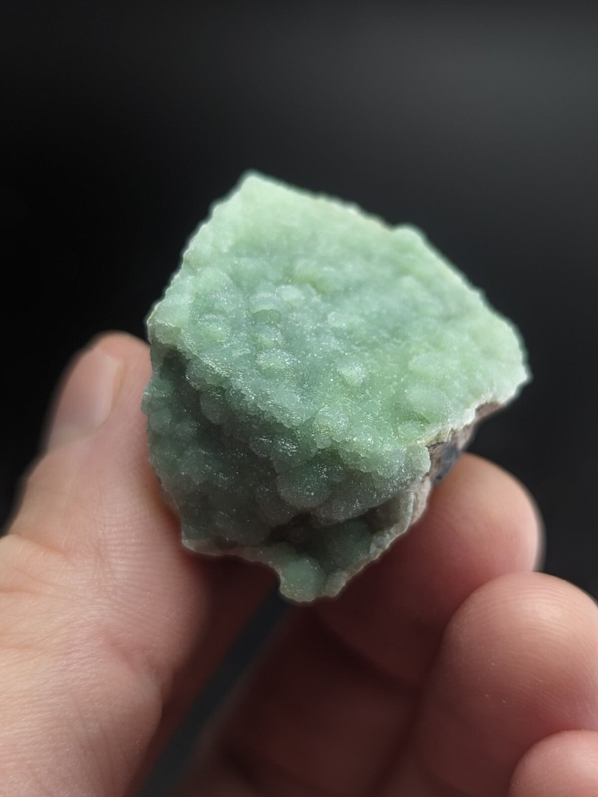 A pale green, textured mineral specimen with a bumpy surface and irregular edges.
