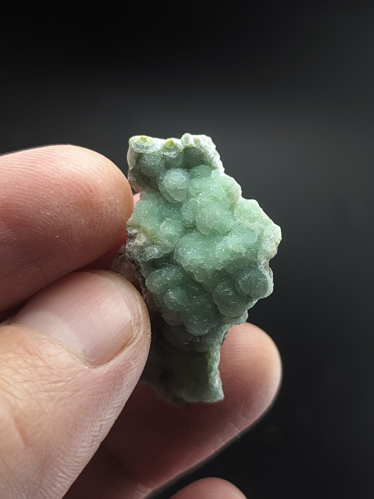 A translucent light green mineral specimen with a clustered, bumpy surface texture.