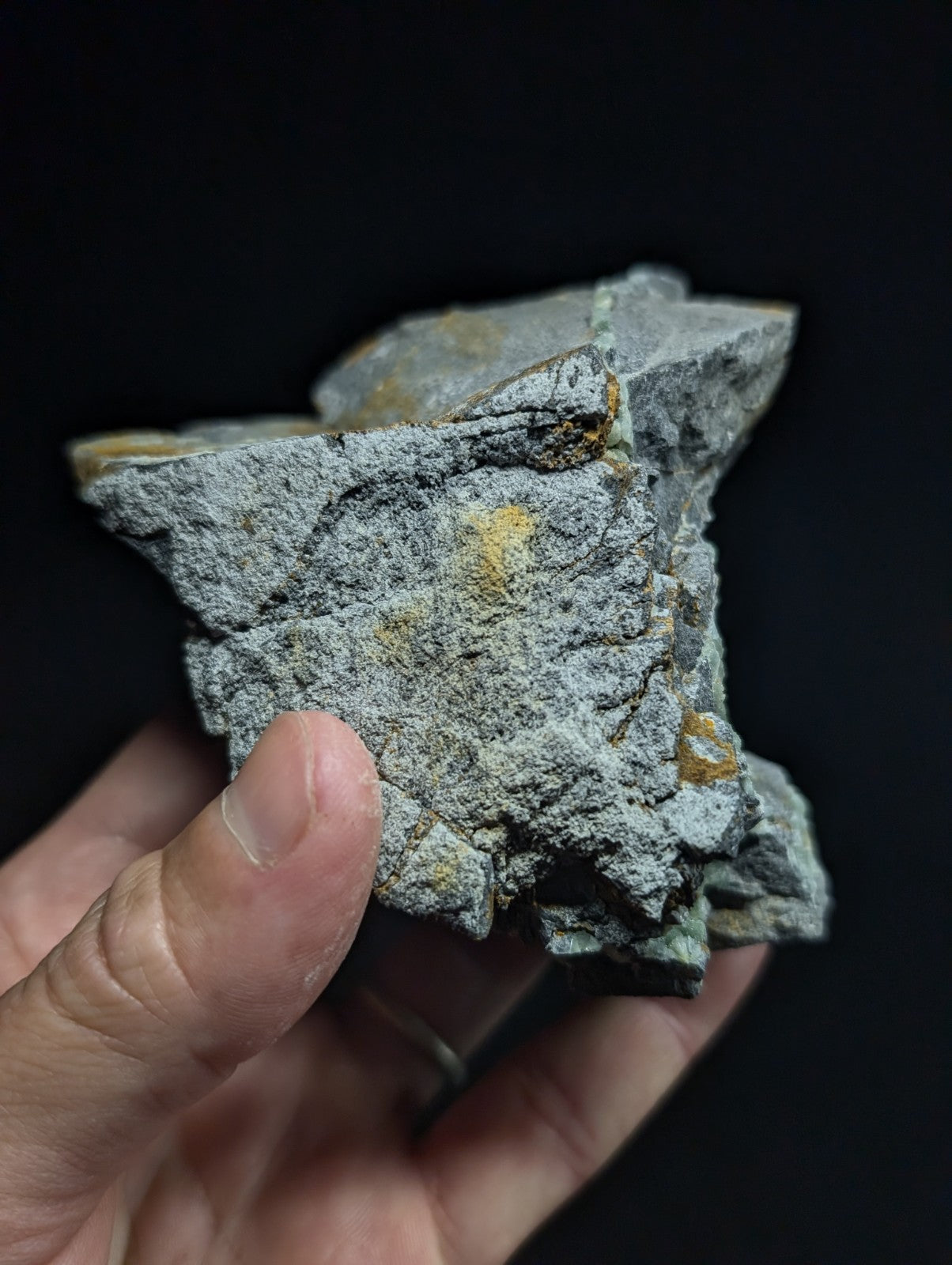 A rough, grayish rock specimen with scattered golden-yellow mineral inclusions.