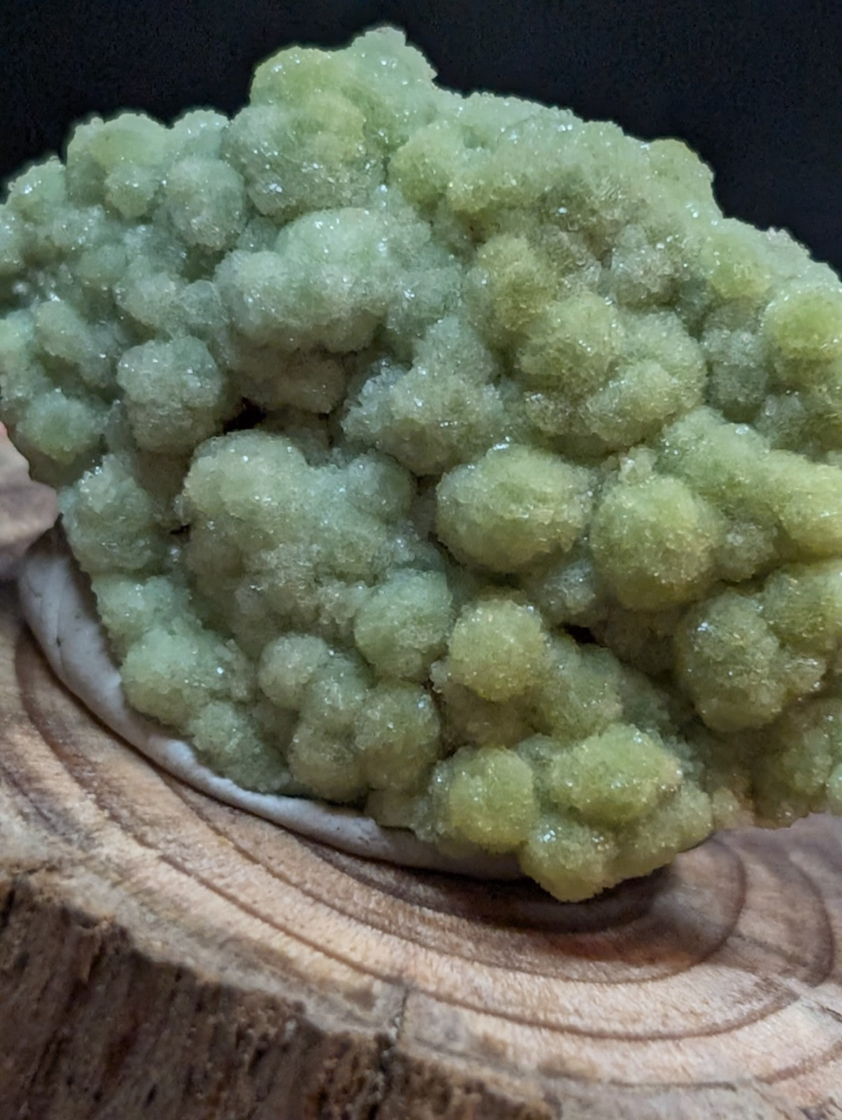 A cluster of translucent, pale green crystals with a sugary texture and rounded formations.