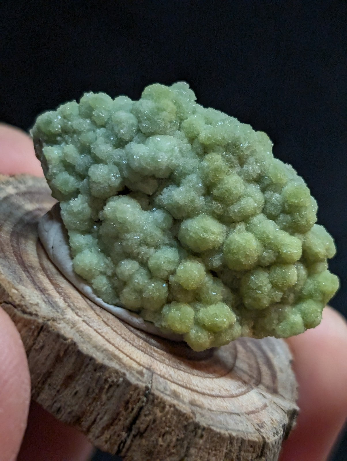A cluster of translucent, pale green mineral crystals with a bumpy, rounded texture.