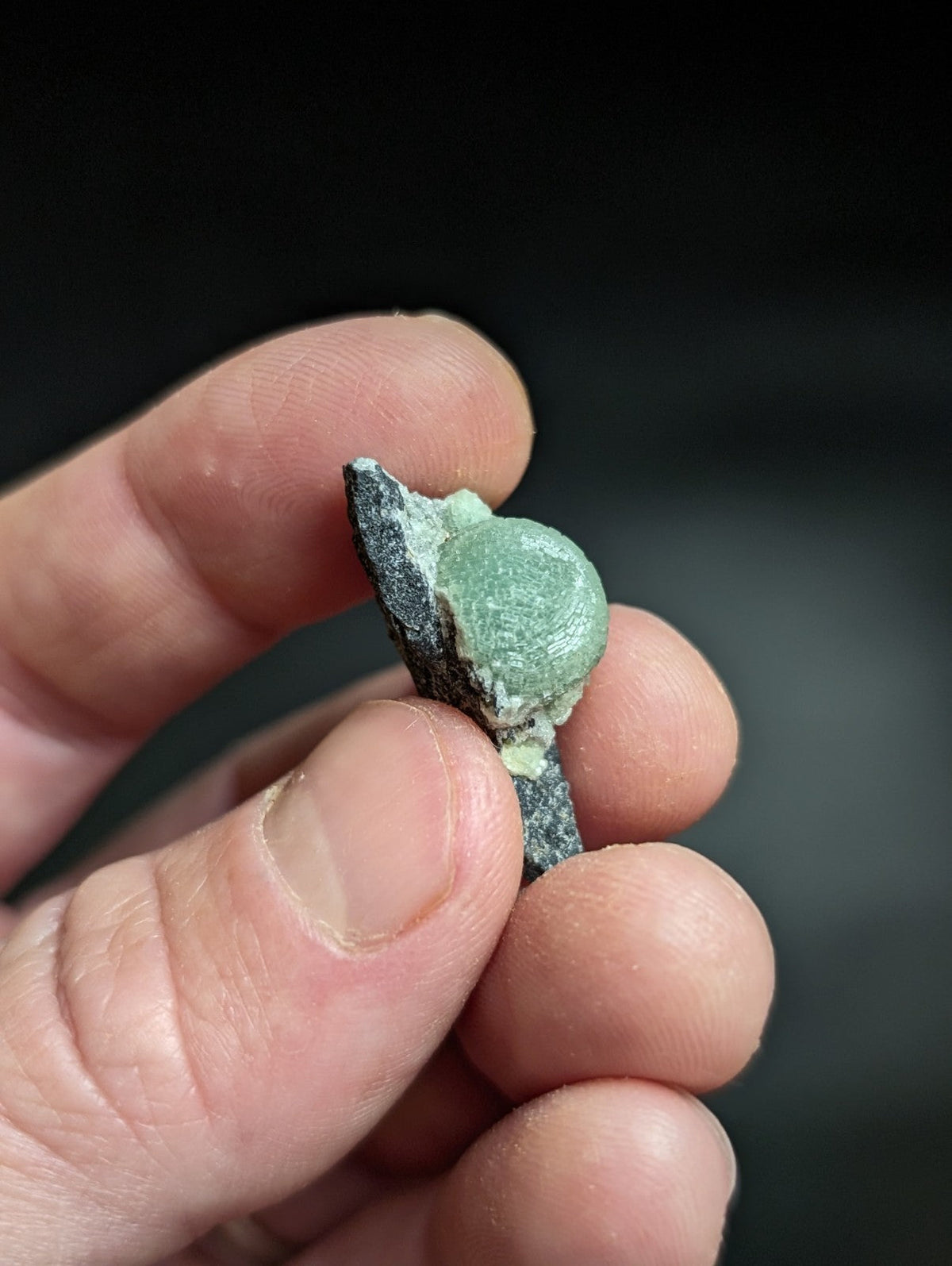 A weathered, greenish patina-coated bronze artifact fragment with a rounded, bulbous end and jagged edges.