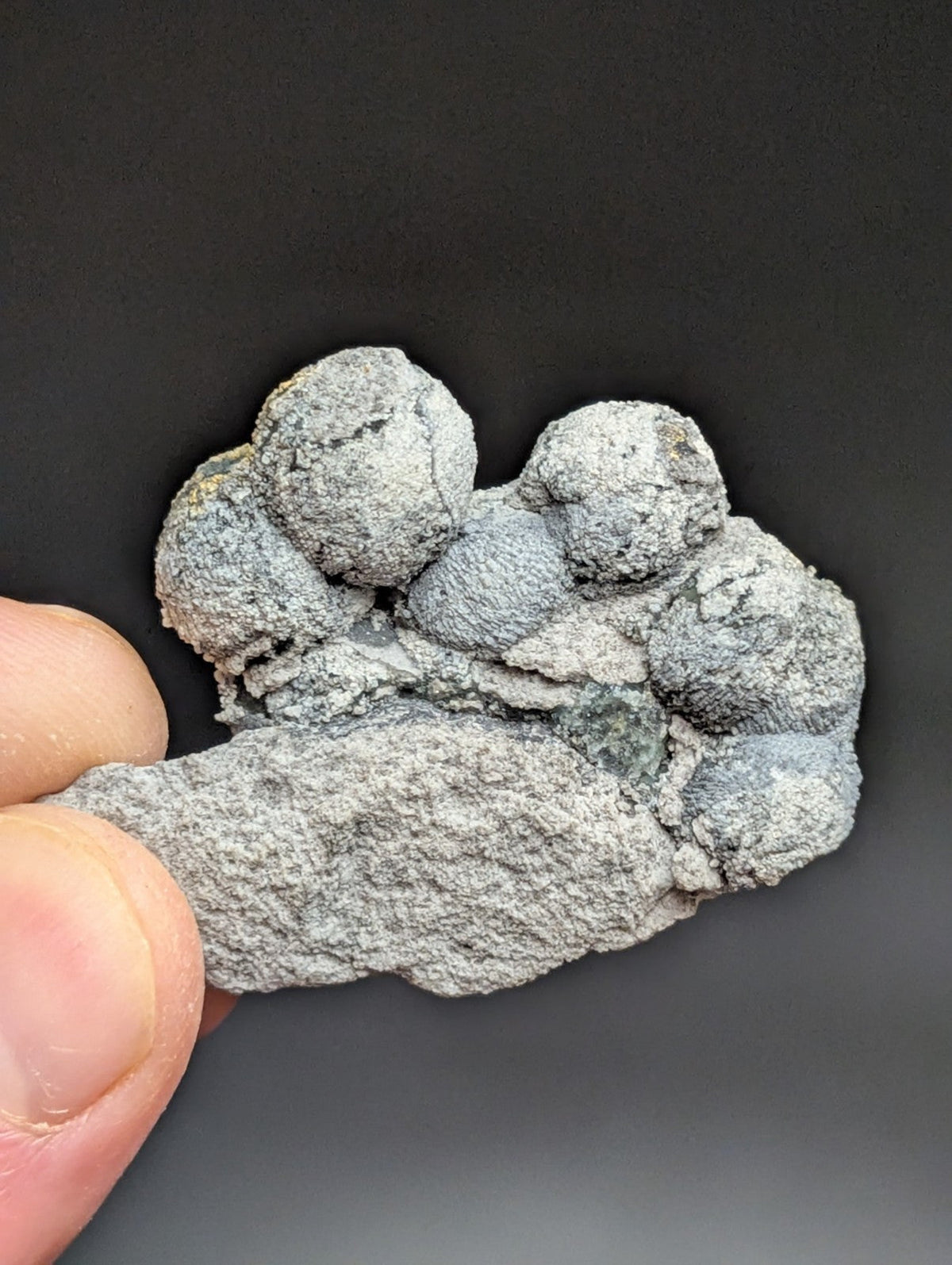 A gray, textured mineral specimen with rounded nodules clustered together.