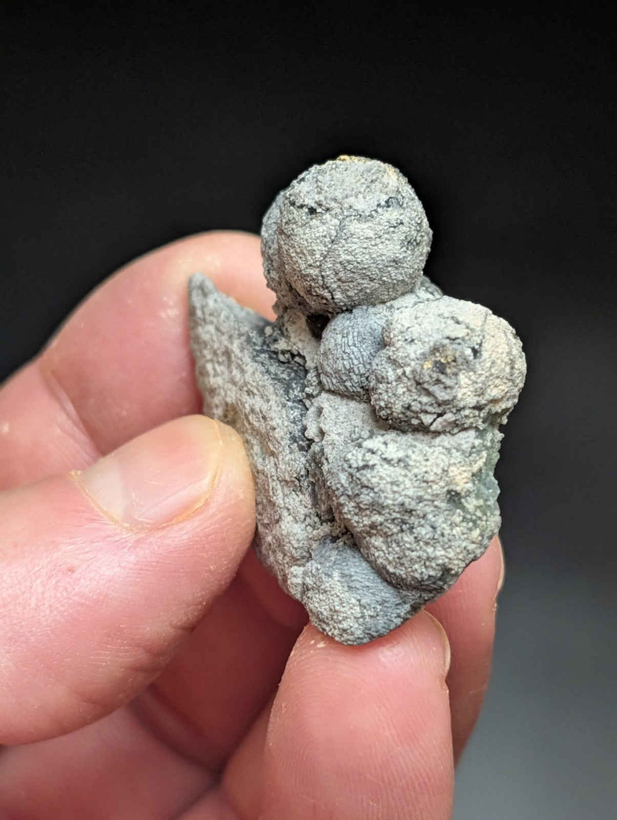 A weathered, grayish-green figurine of a small angel with wings and rounded features.