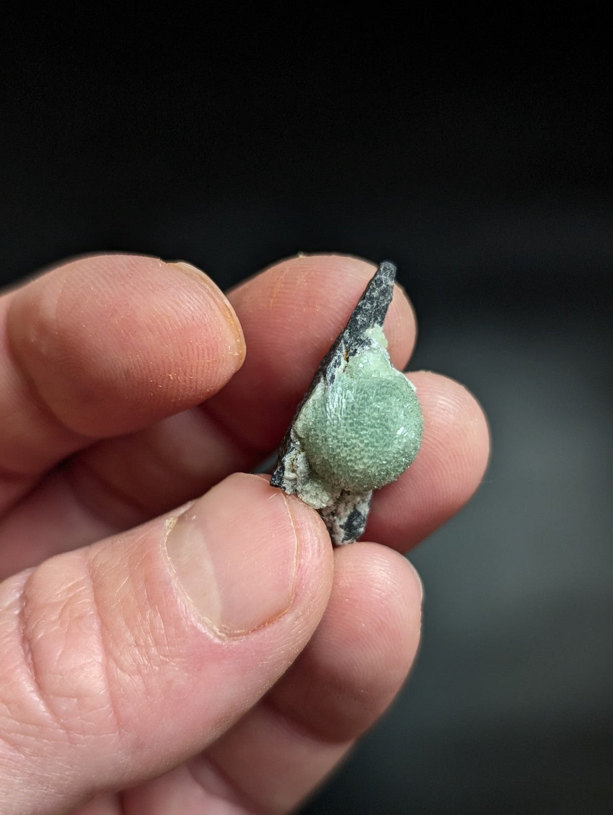 A weathered, verdigris-coated bronze artifact with a textured surface and pointed tip.