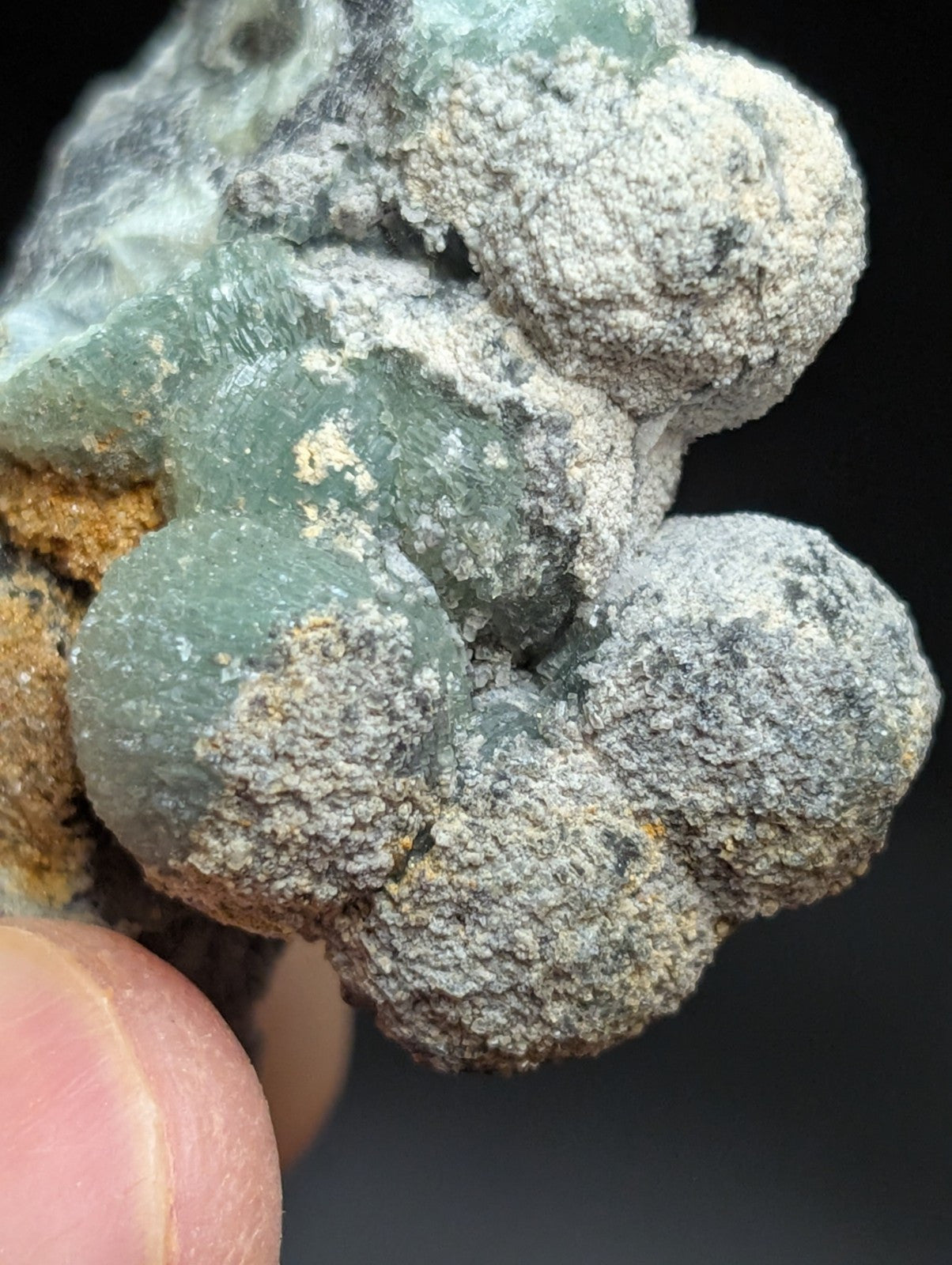 A cluster of translucent green and gray mineral formations with a rough, textured surface.