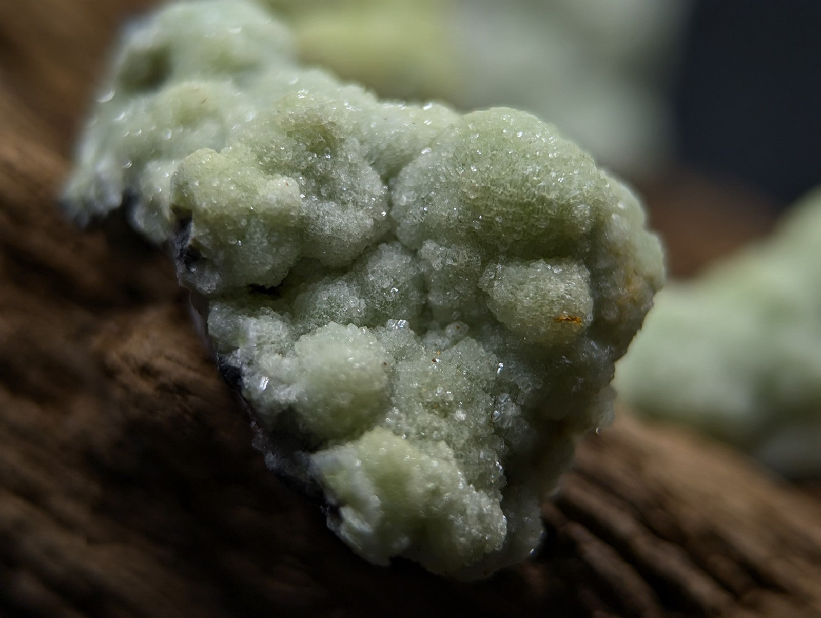 A cluster of pale green, crystalline minerals with a rough, textured surface.