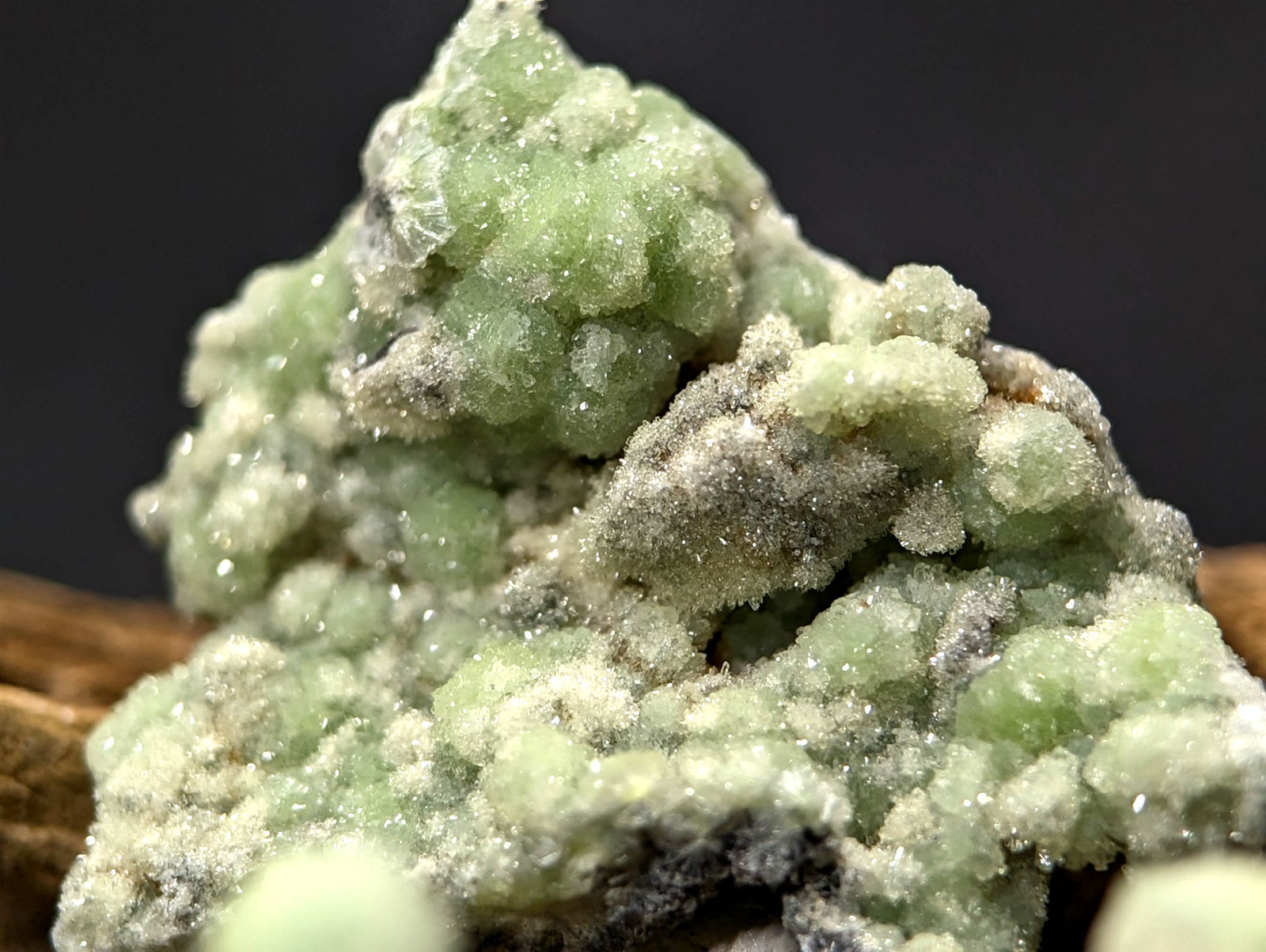 A cluster of pale green, crystalline minerals with a rough, textured surface and some grayish patches.