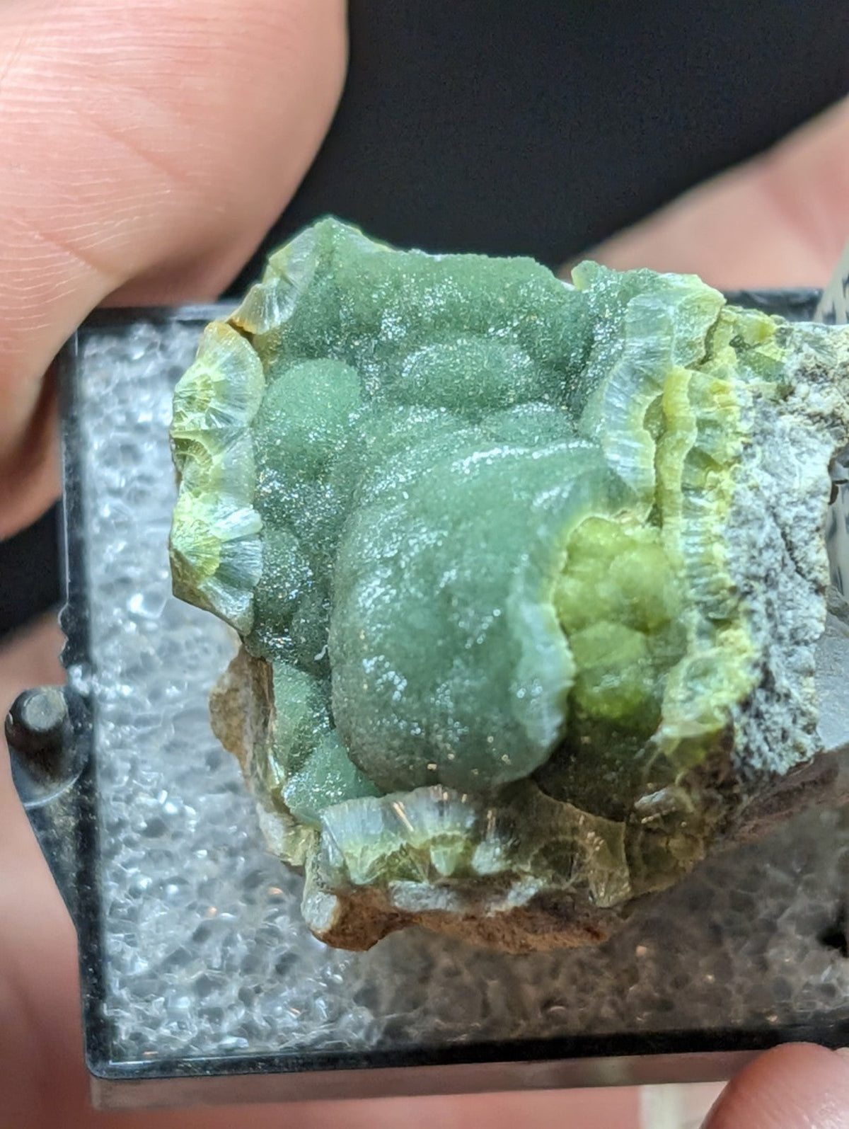 A translucent green mineral specimen with a crystalline, layered texture and subtle yellowish highlights.