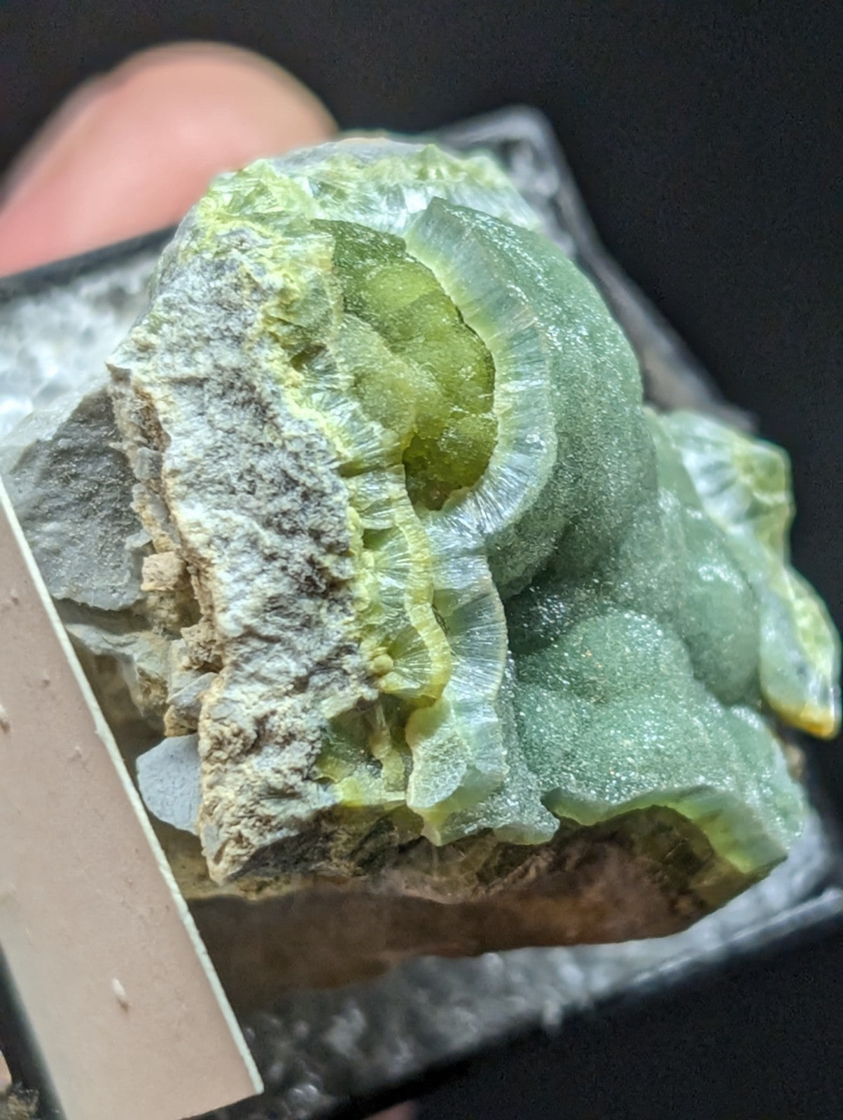 A translucent green and yellow mineral specimen with a crystalline, layered structure.