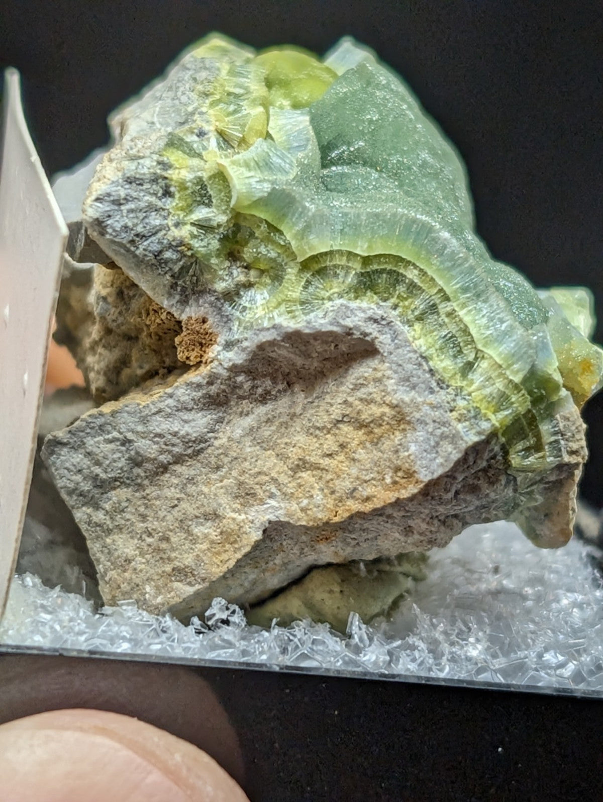 A vibrant green, translucent fluorite crystal formation with layered bands and a rough gray matrix base.