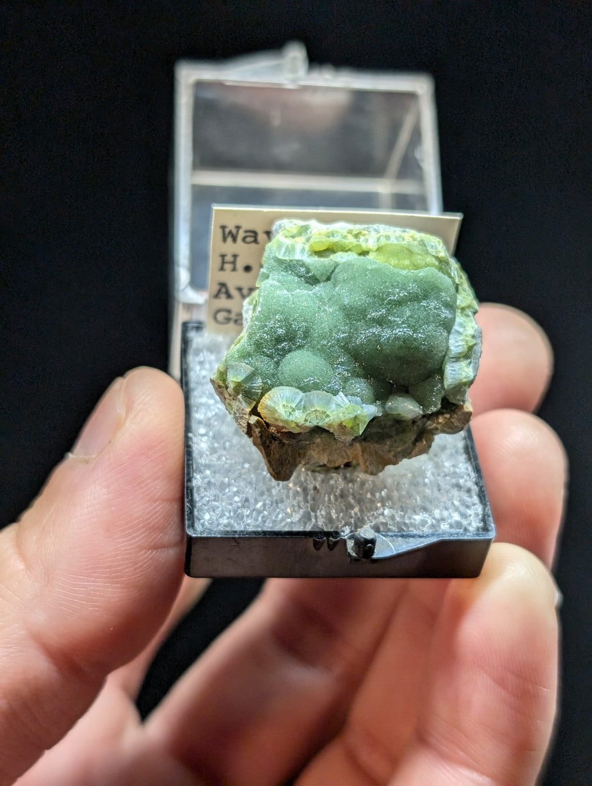 A rough, greenish mineral specimen with a textured surface and crystalline formations.