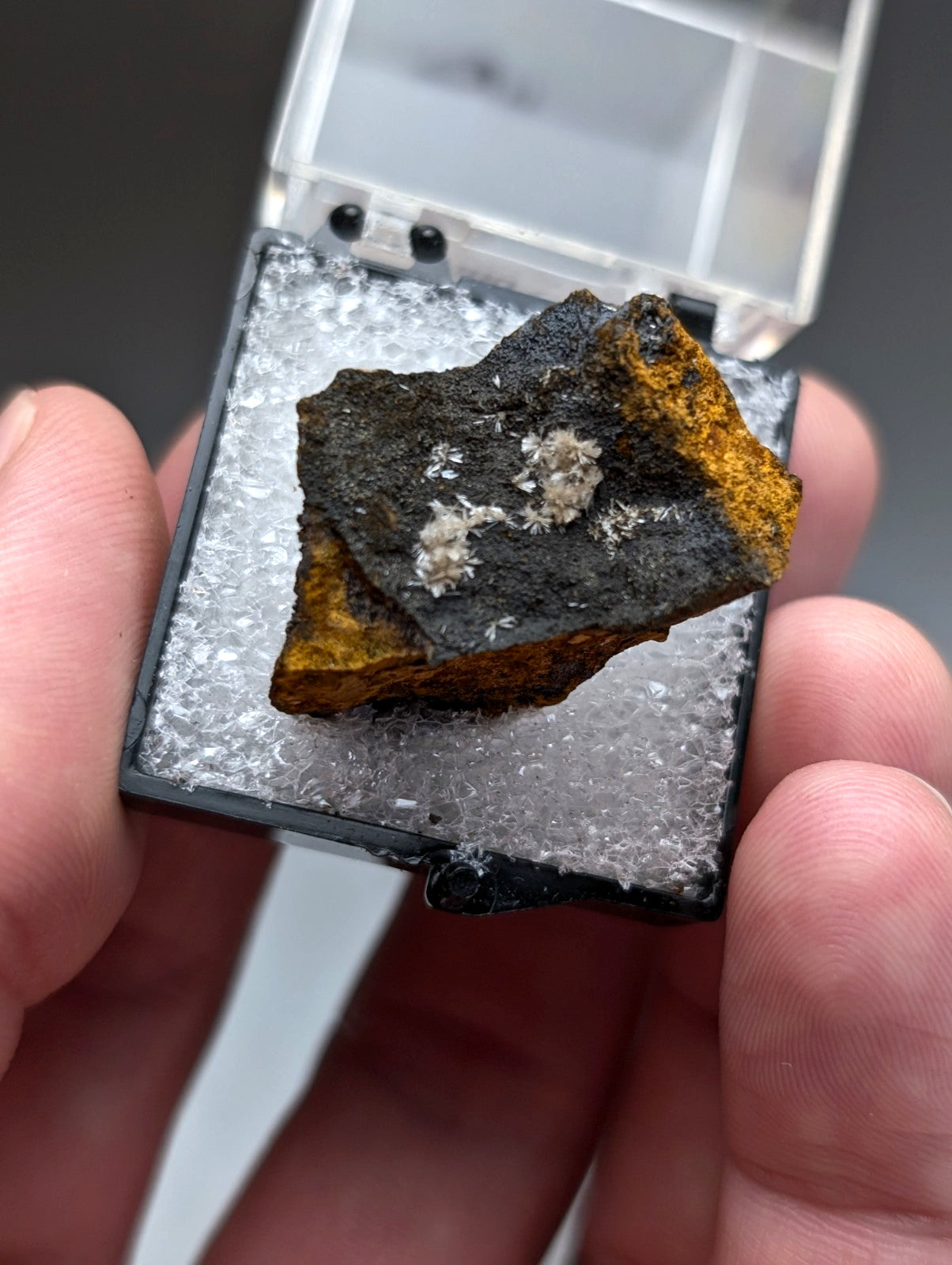 A dark irregular wavellite mineral with orange and white crystalline patches from potash sulphur springs arkansas