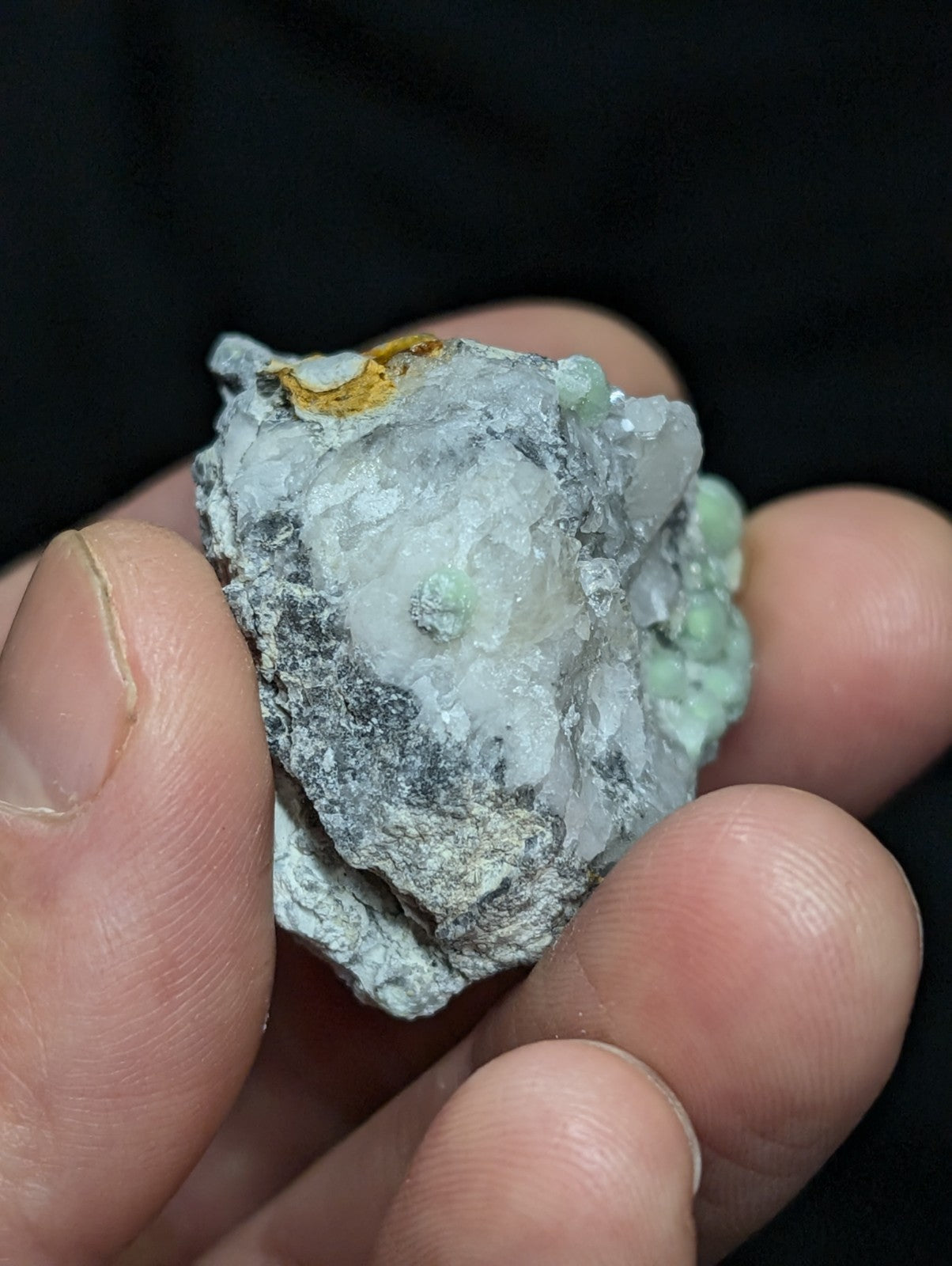 A rough, irregularly shaped mineral specimen with a mix of grayish-white and pale green crystalline formations.