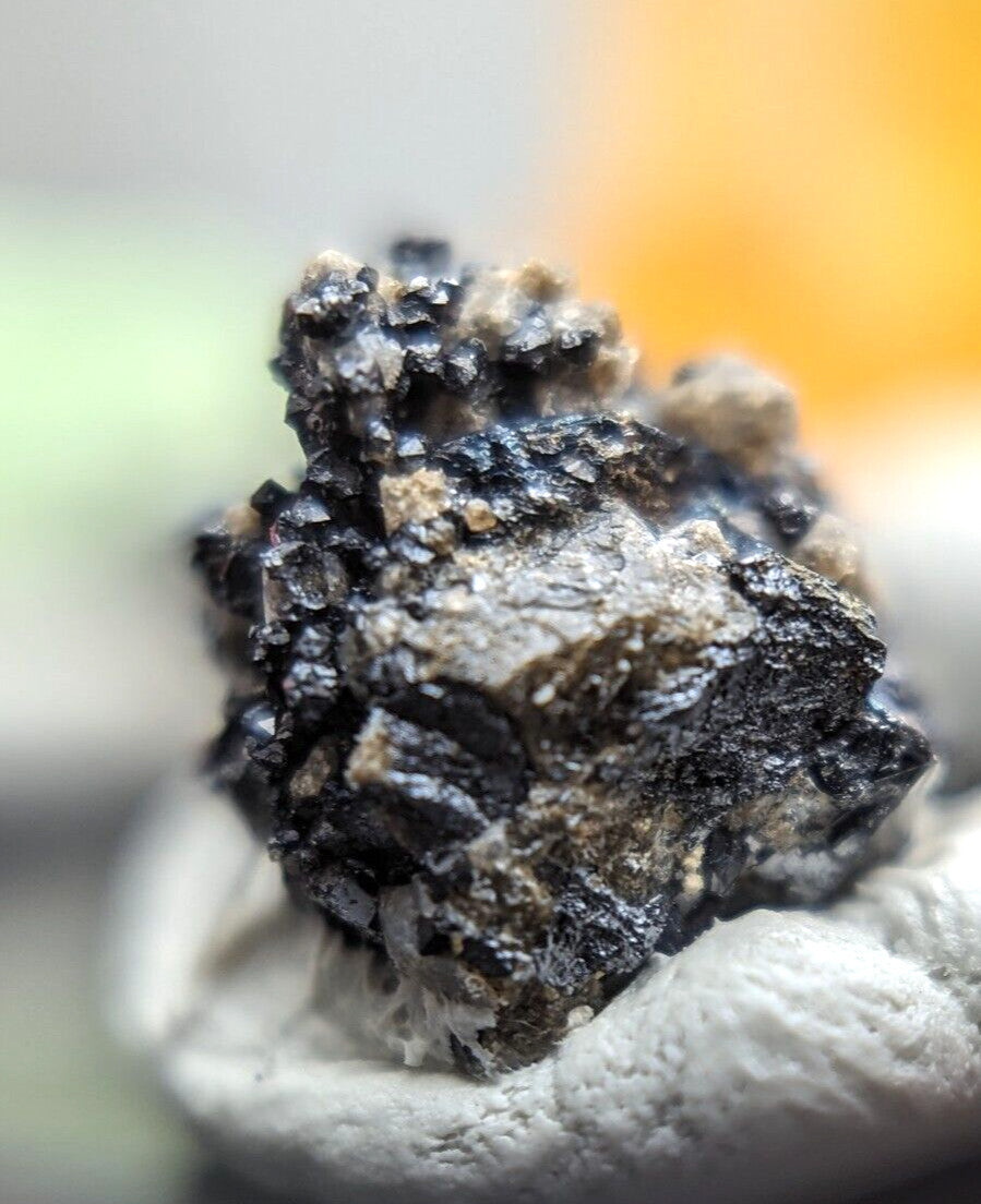 A rugged, irregularly shaped mineral specimen with a mix of dark black and grayish-brown hues, featuring rough, crystalline textures.