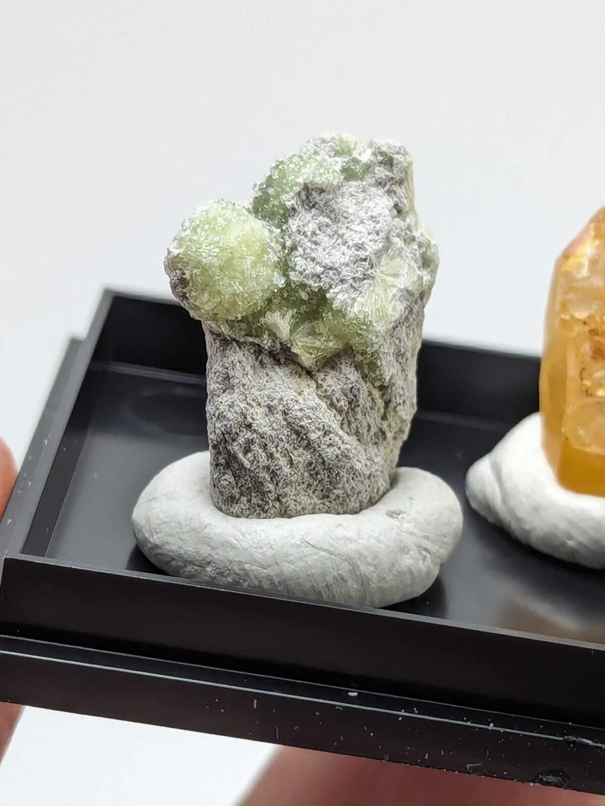 A green, crystalline mineral specimen with a rough gray matrix base.
