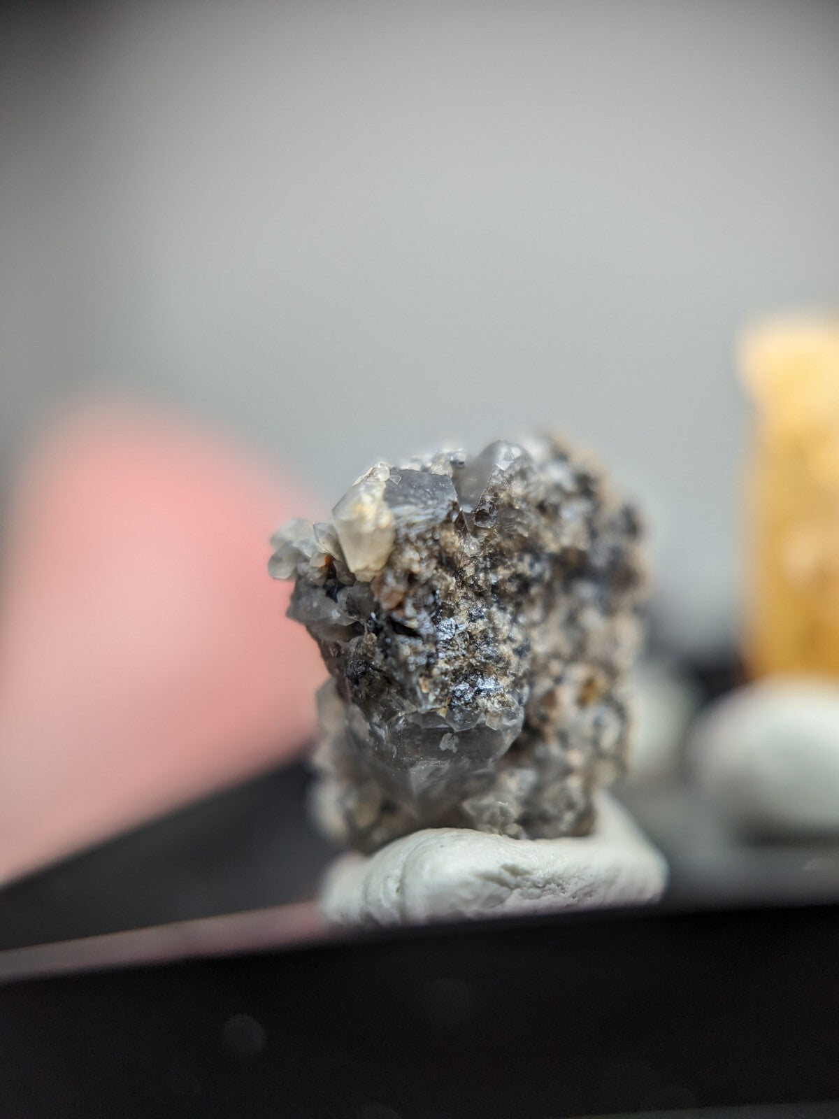 A gray, crystalline mineral specimen with translucent facets and a rough, earthy base.