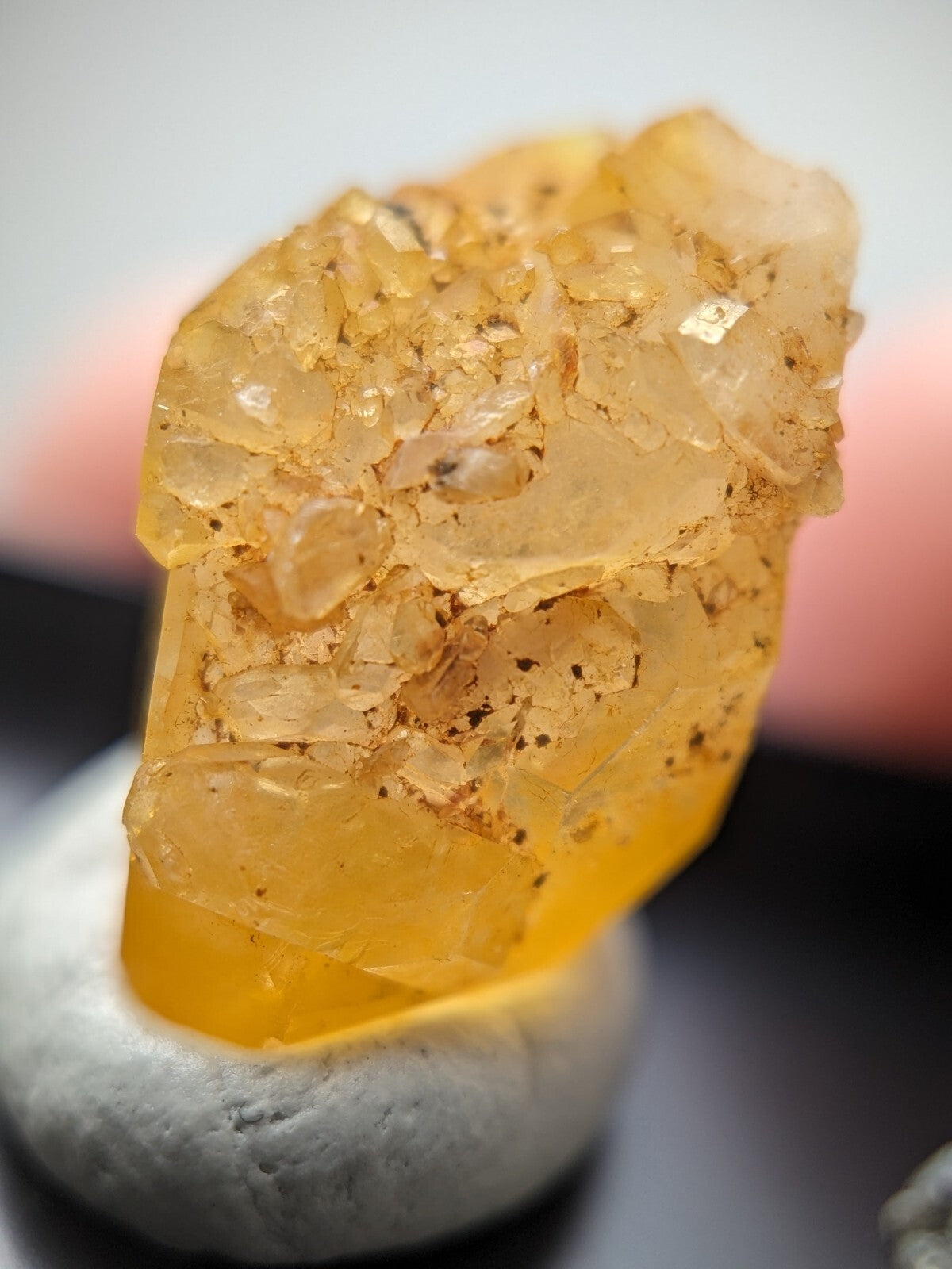 A translucent golden-yellow crystal cluster with a rough, faceted surface and embedded dark specks.
