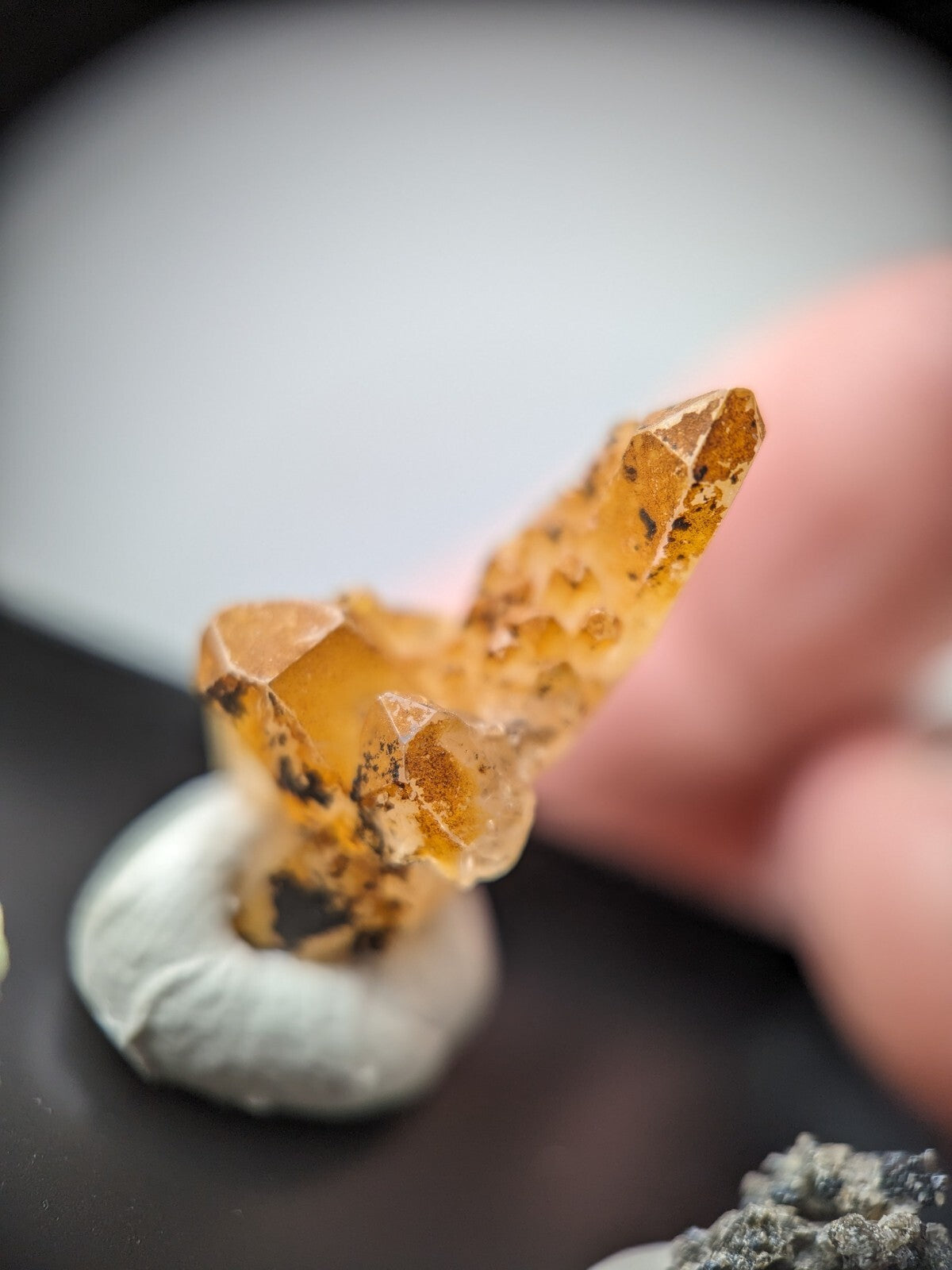 A translucent amber-colored crystal cluster with a faceted, pointed structure and dark inclusions.