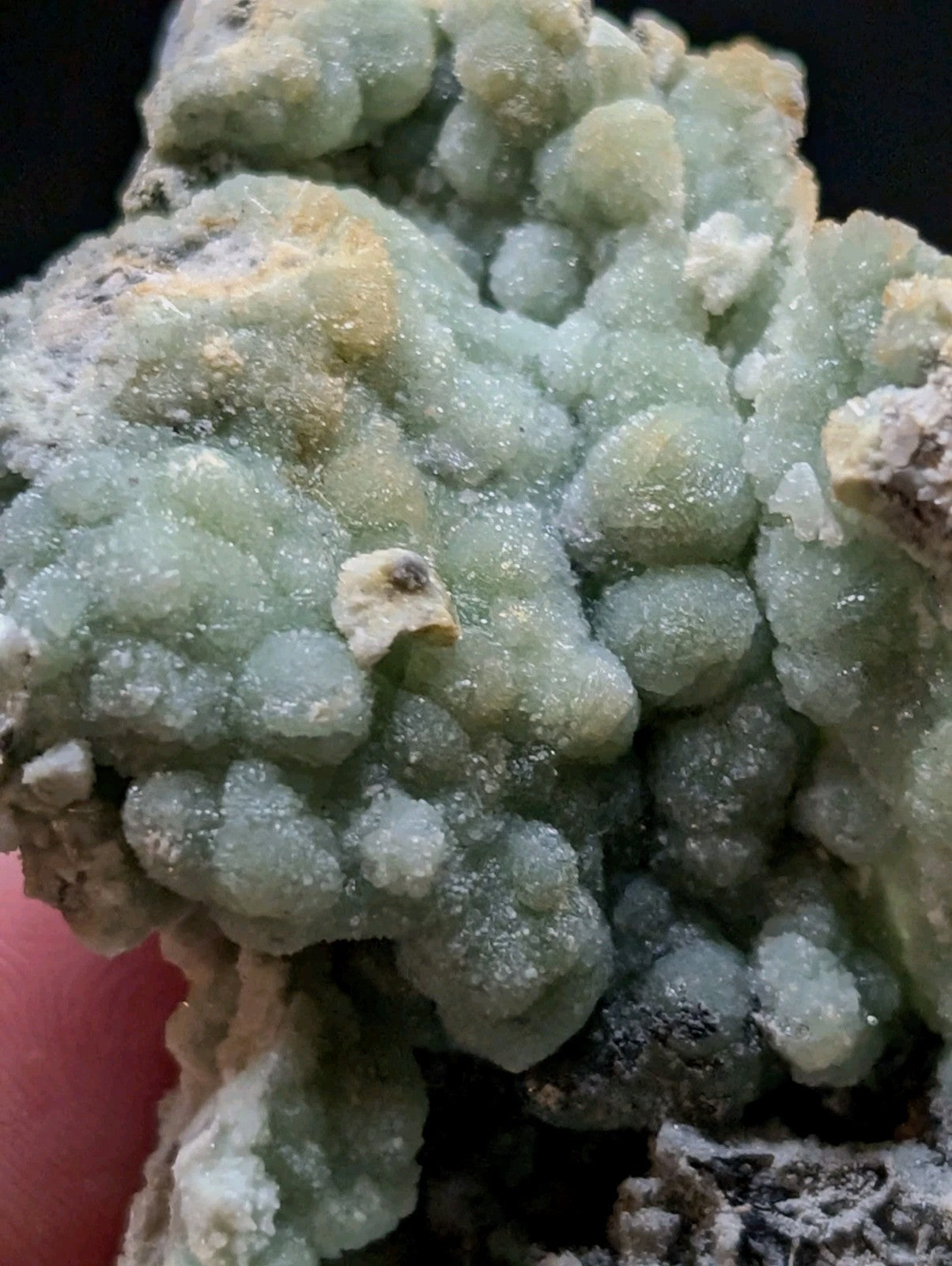 A textured, light green mineral specimen with a crystalline, bubbly surface and subtle yellowish patches.