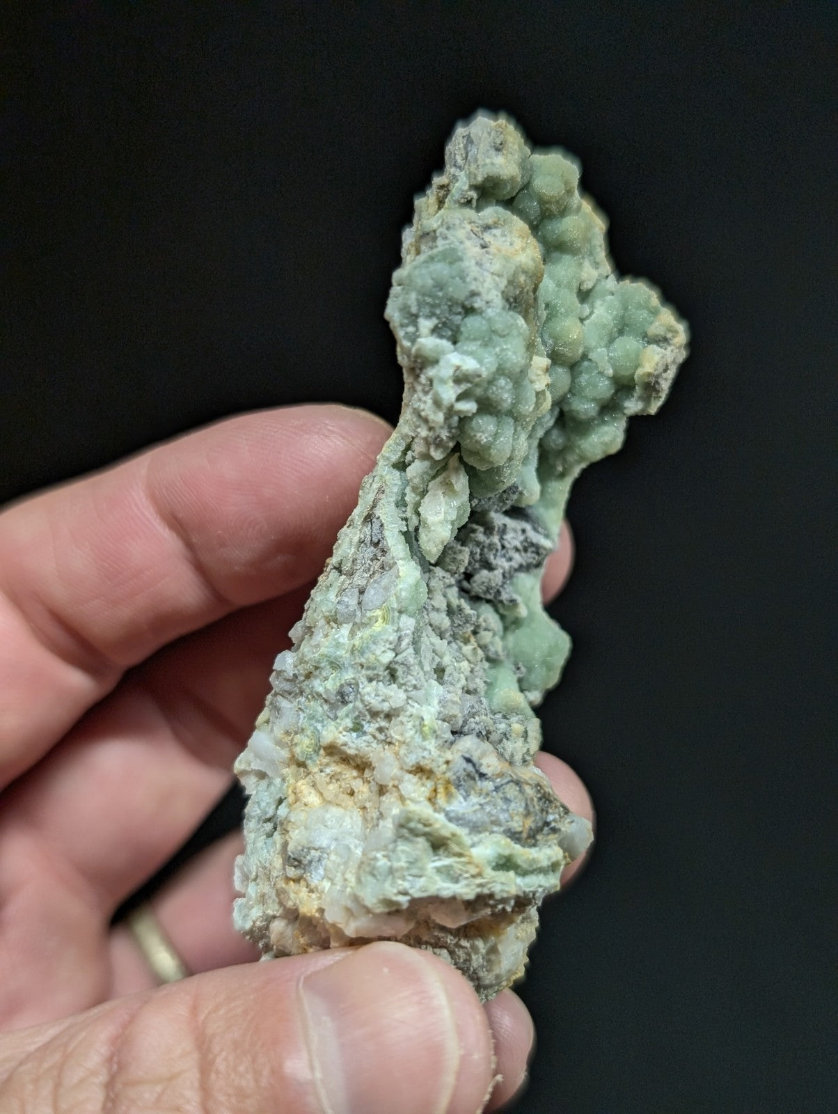 A textured, light green mineral specimen with a rough, clustered surface and subtle yellowish patches.