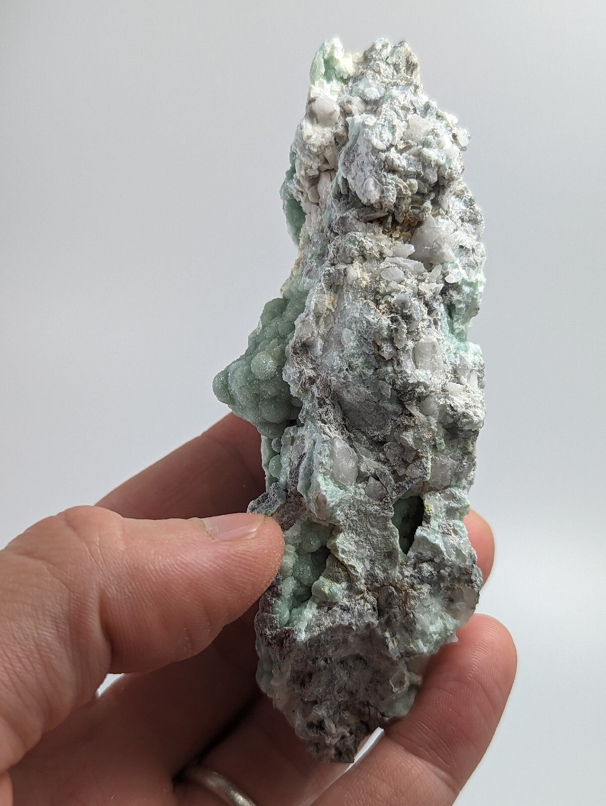 A rough, irregularly shaped mineral specimen with a mottled green and gray surface.