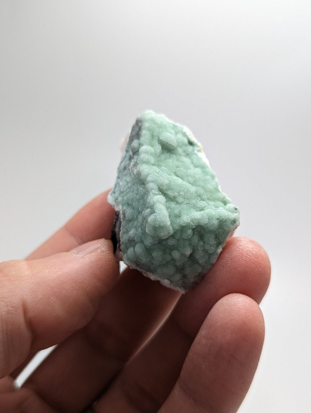 A pale green, textured mineral specimen with a rough, crystalline surface.