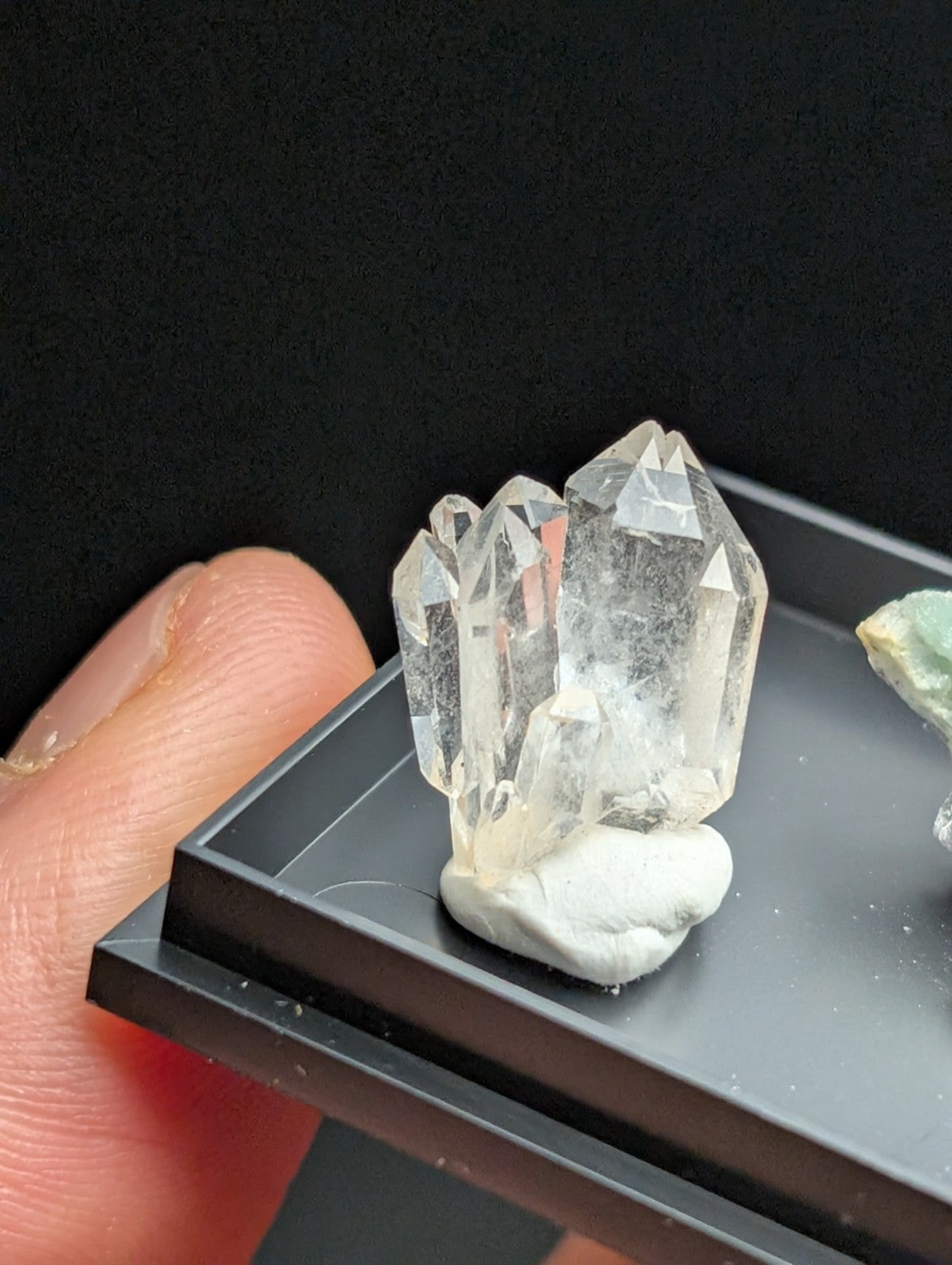 Clear quartz crystal cluster with pointed, faceted points and a white base.