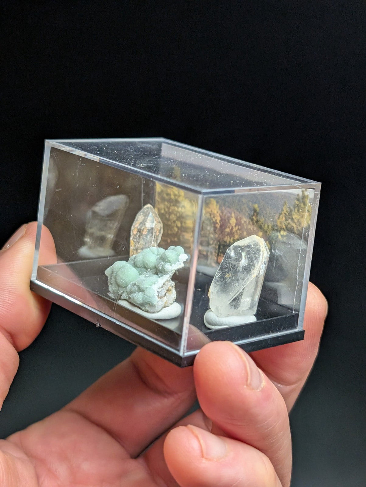 Clear acrylic display case holding three mineral specimens