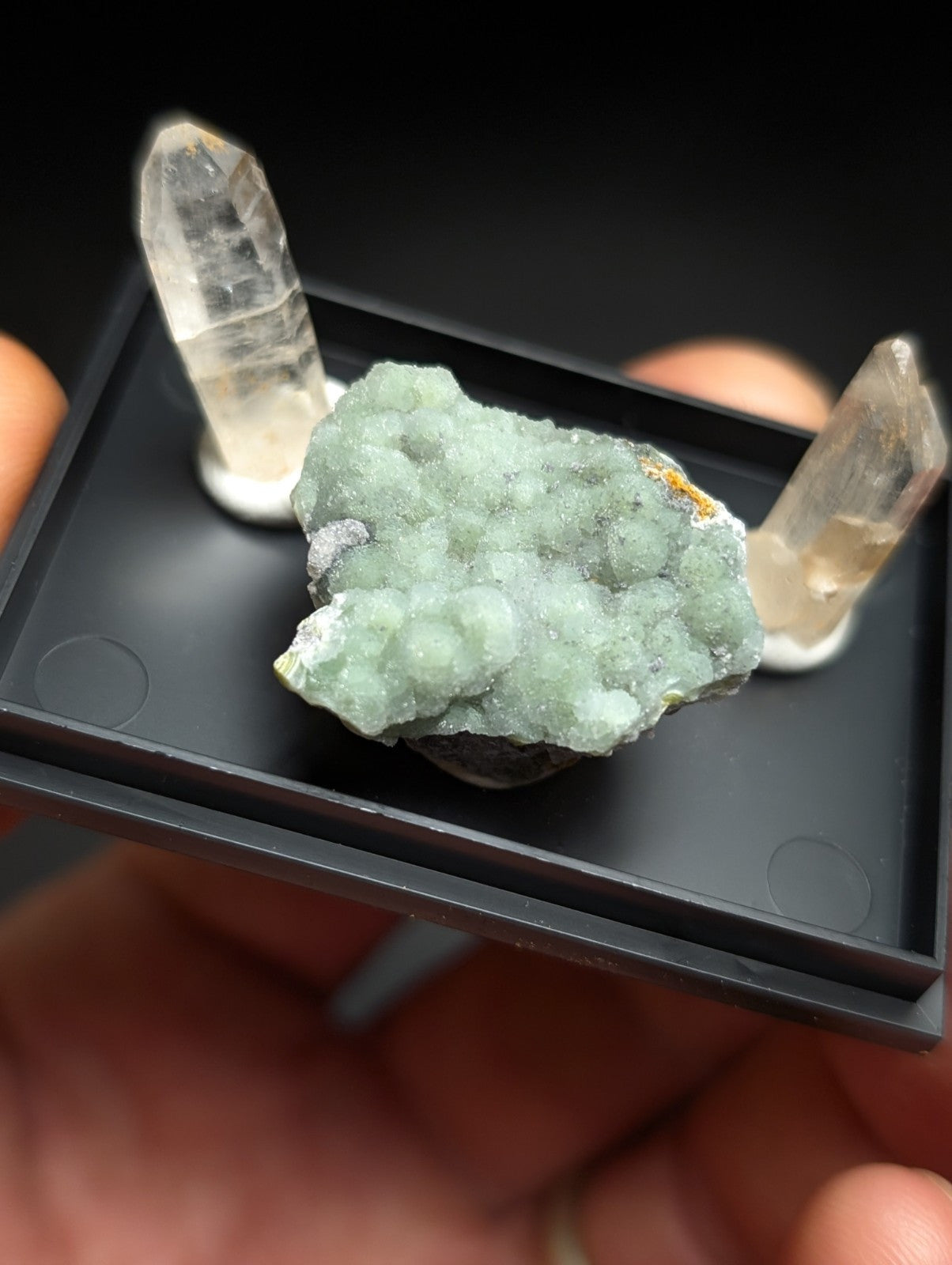 A pale green, crystalline mineral specimen with a textured surface and small yellowish inclusions.