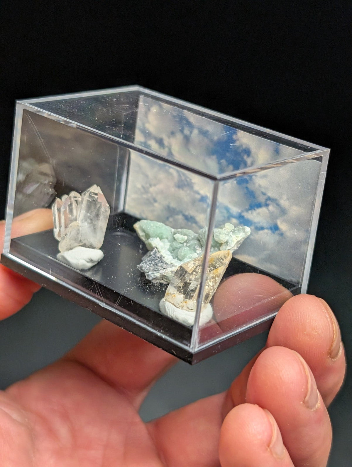 Clear acrylic display case holding mineral specimens.