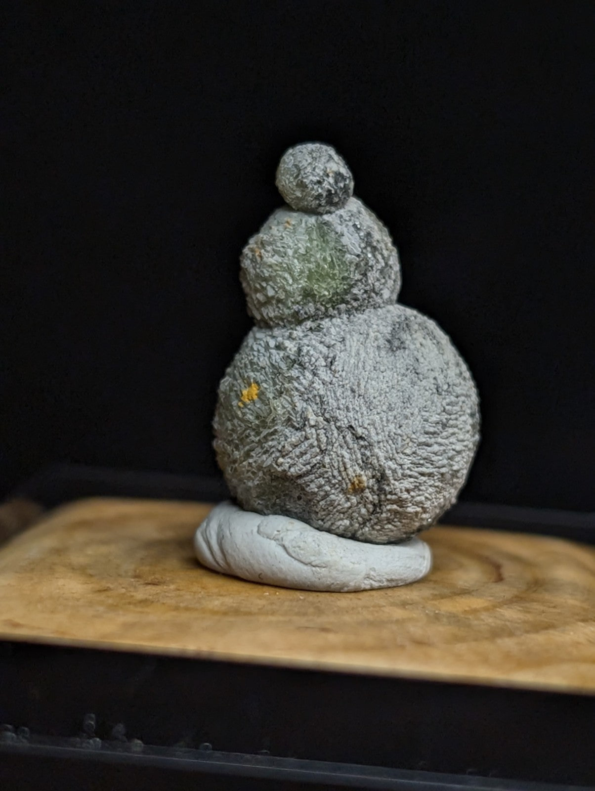 Gray, textured stone sculpture with a stacked, rounded form and subtle greenish tint.