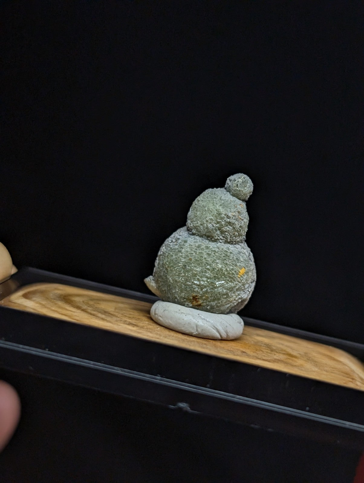 A textured, moss-green stone figurine shaped like a stylized bird with a rounded body and small head.