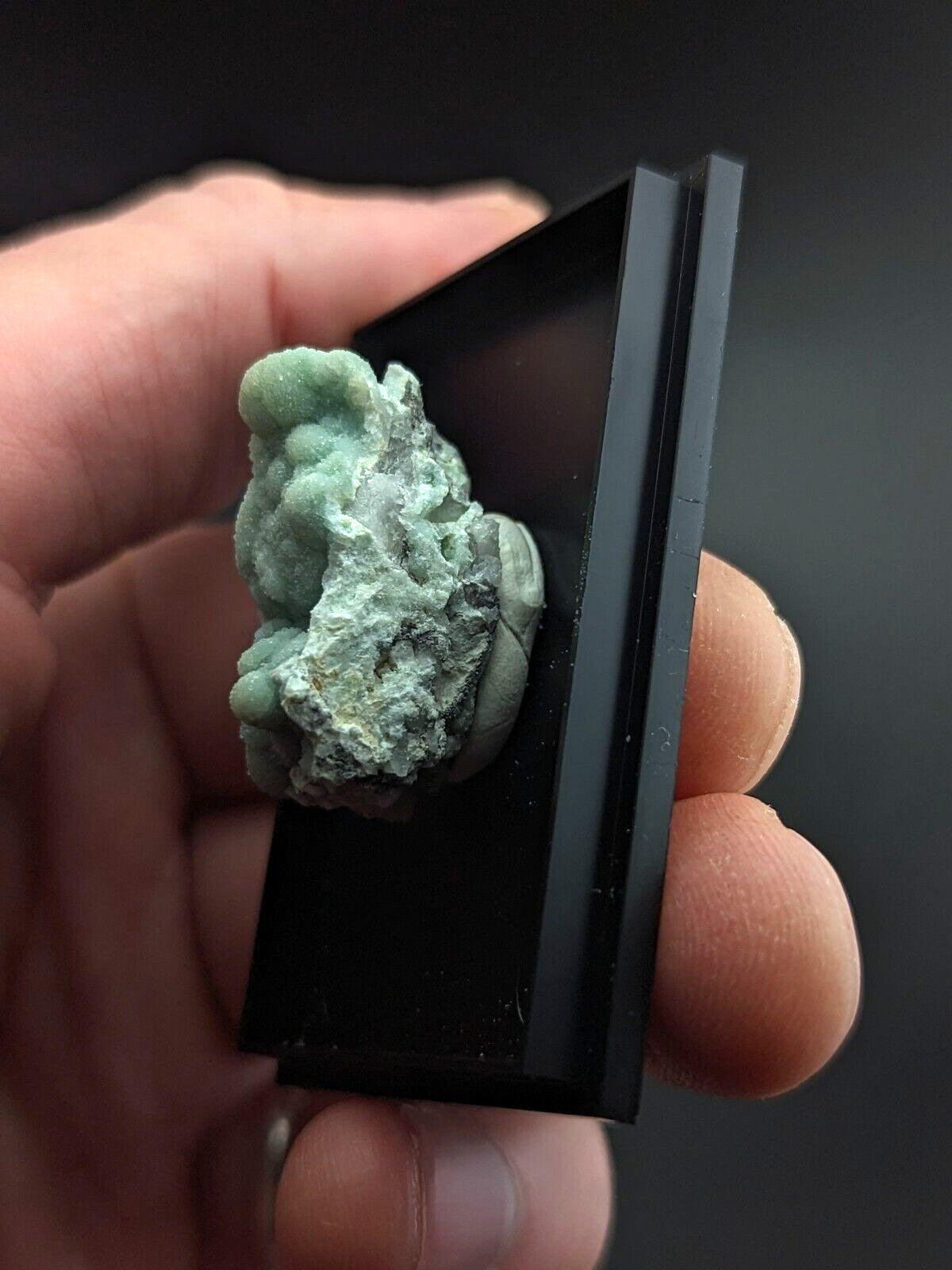 A textured, light green mineral specimen with a rough, irregular surface and subtle white veining.