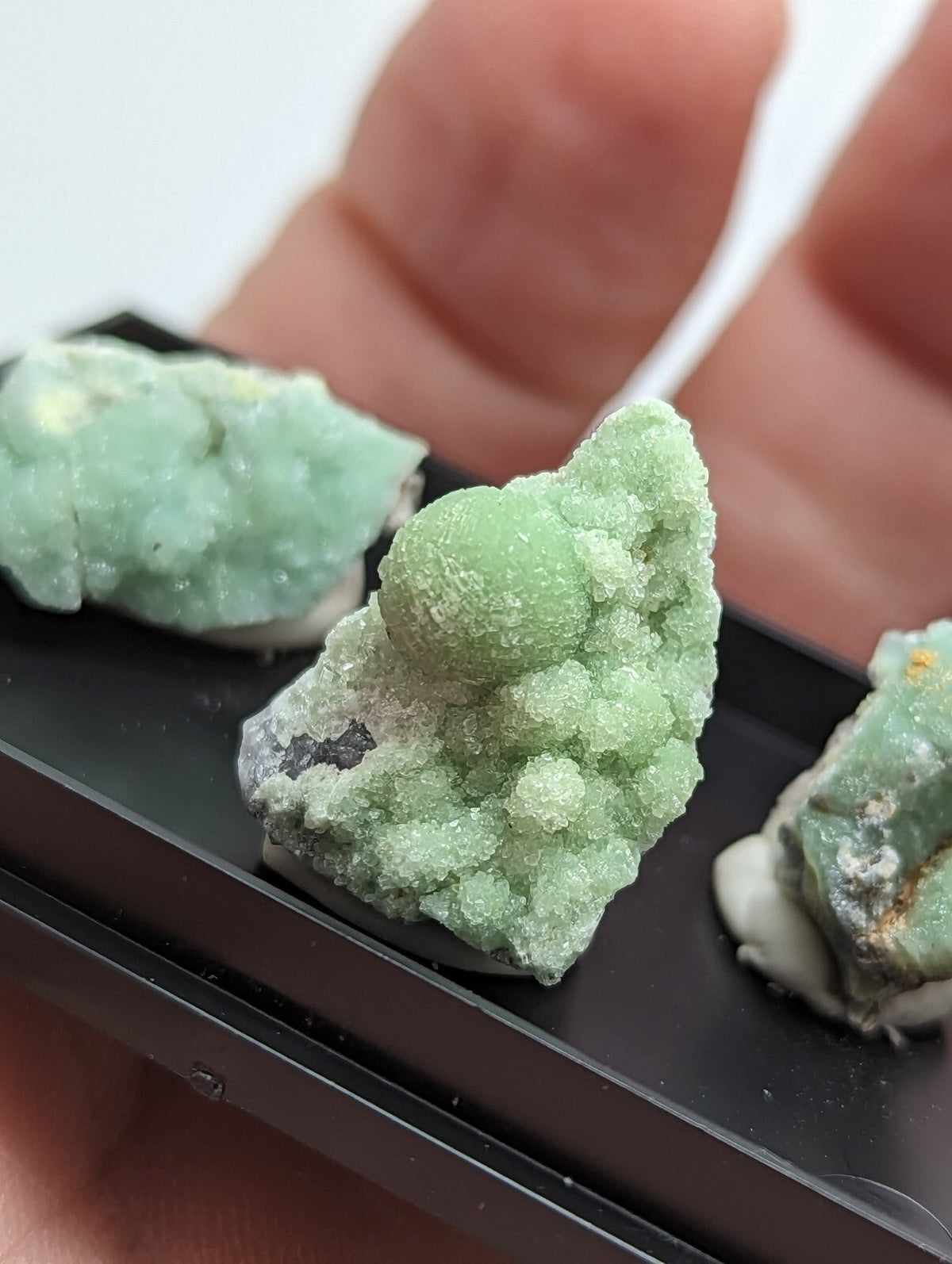 A cluster of light green, crystalline mineral specimens with a rough, textured surface and some translucent areas.