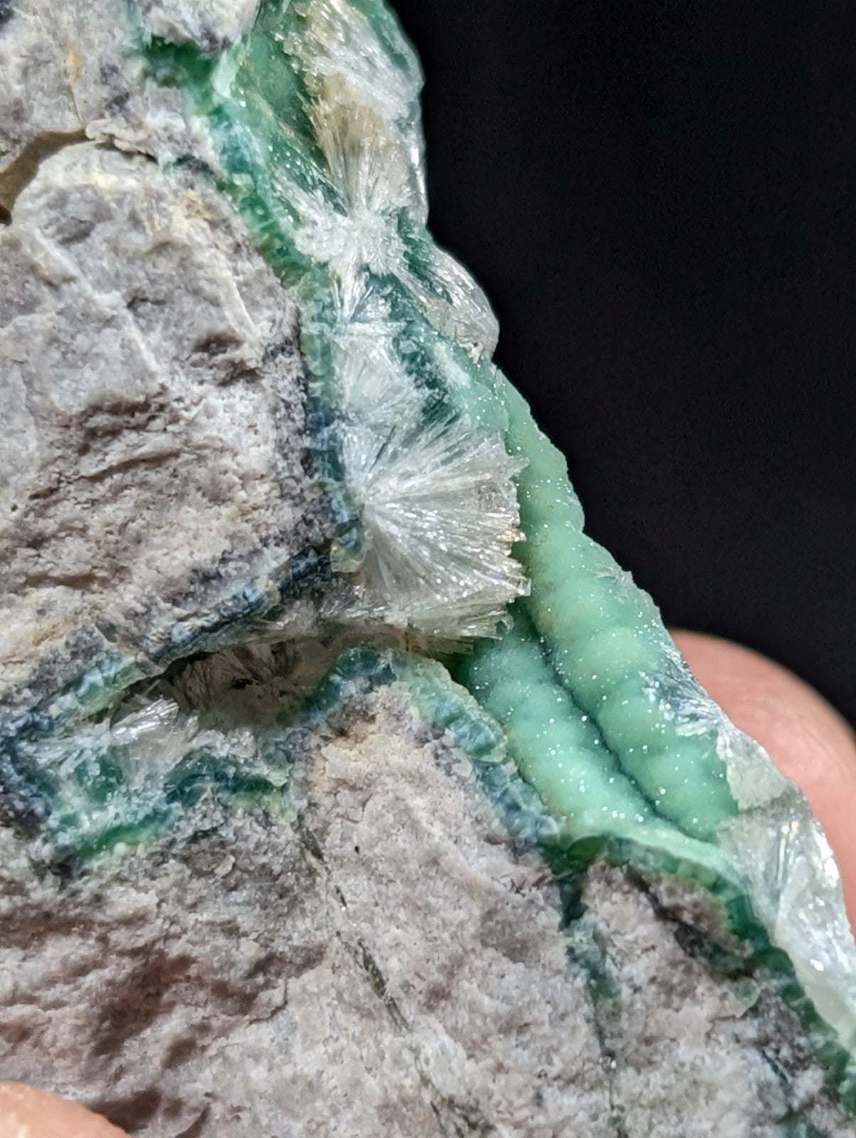 A translucent green mineral specimen with crystalline formations embedded in a grayish rock matrix.