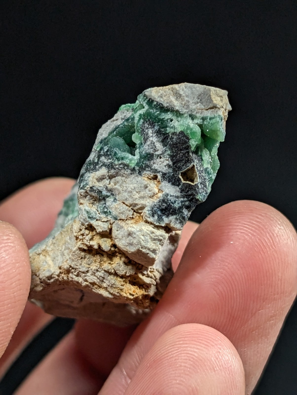 A rough, irregularly shaped piece of green jade with visible mineral matrix and natural fractures.